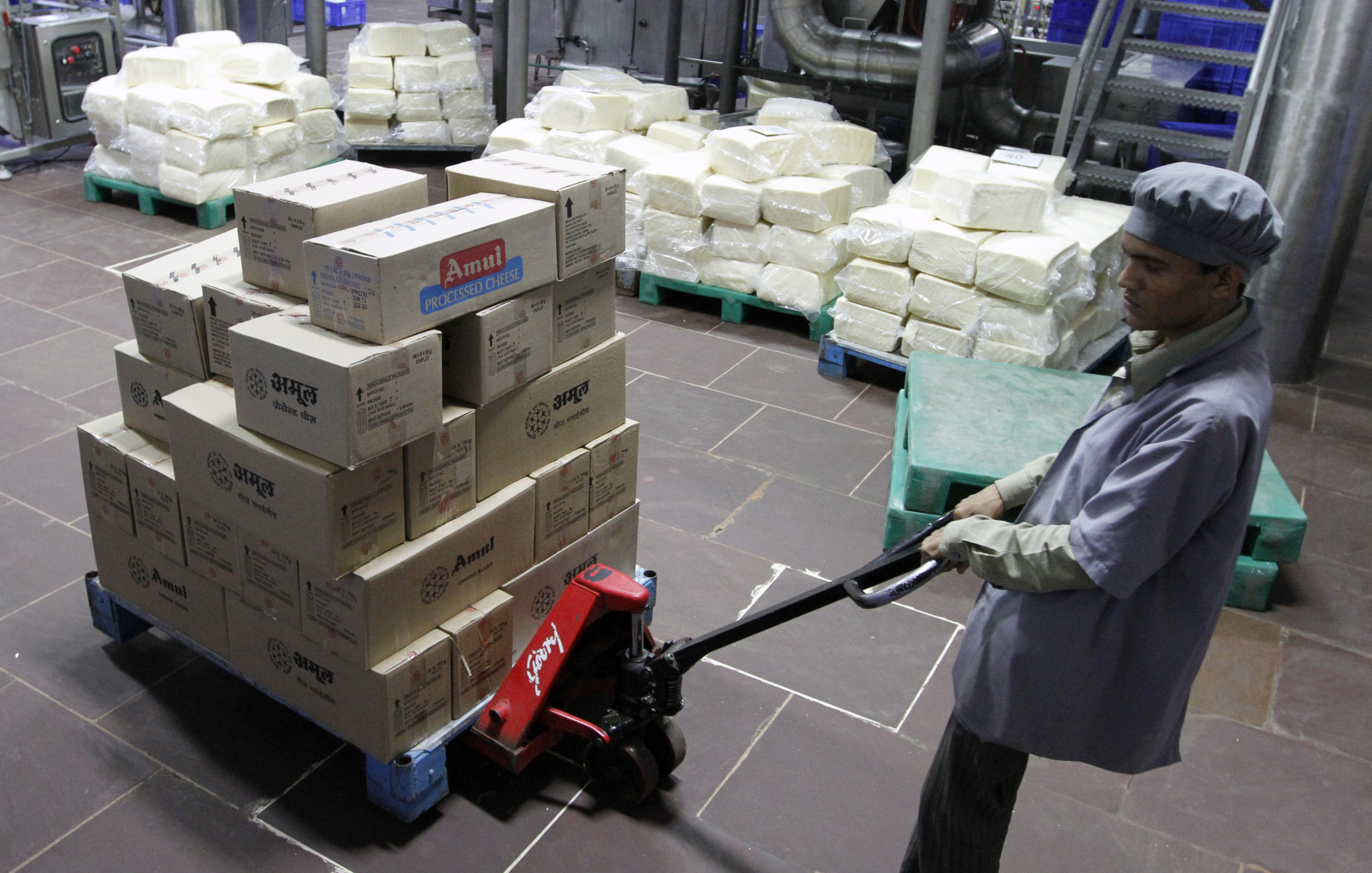 A worker moves a trolley loaded with packed processed cheese during a media tour to Amul satellite dairy in Khatraj village