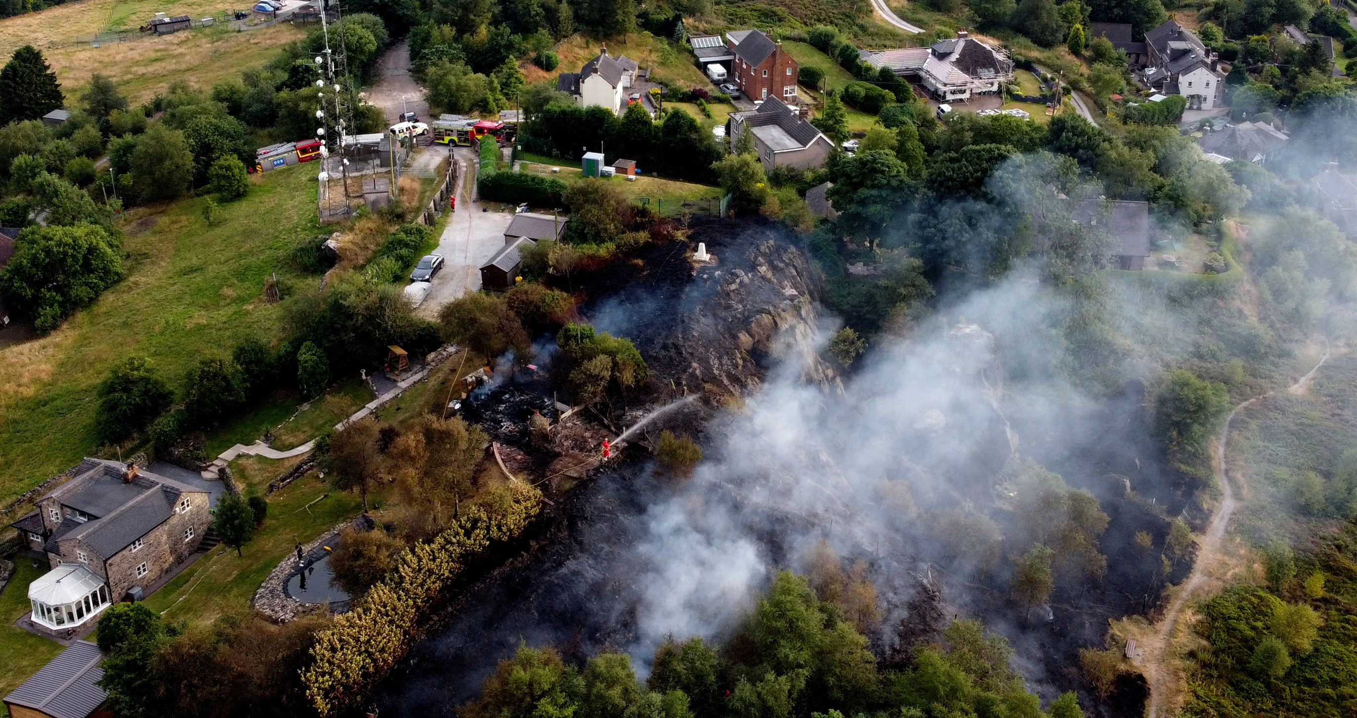 Firefighters tackle a grass fire during the heatwave in Mow Cop