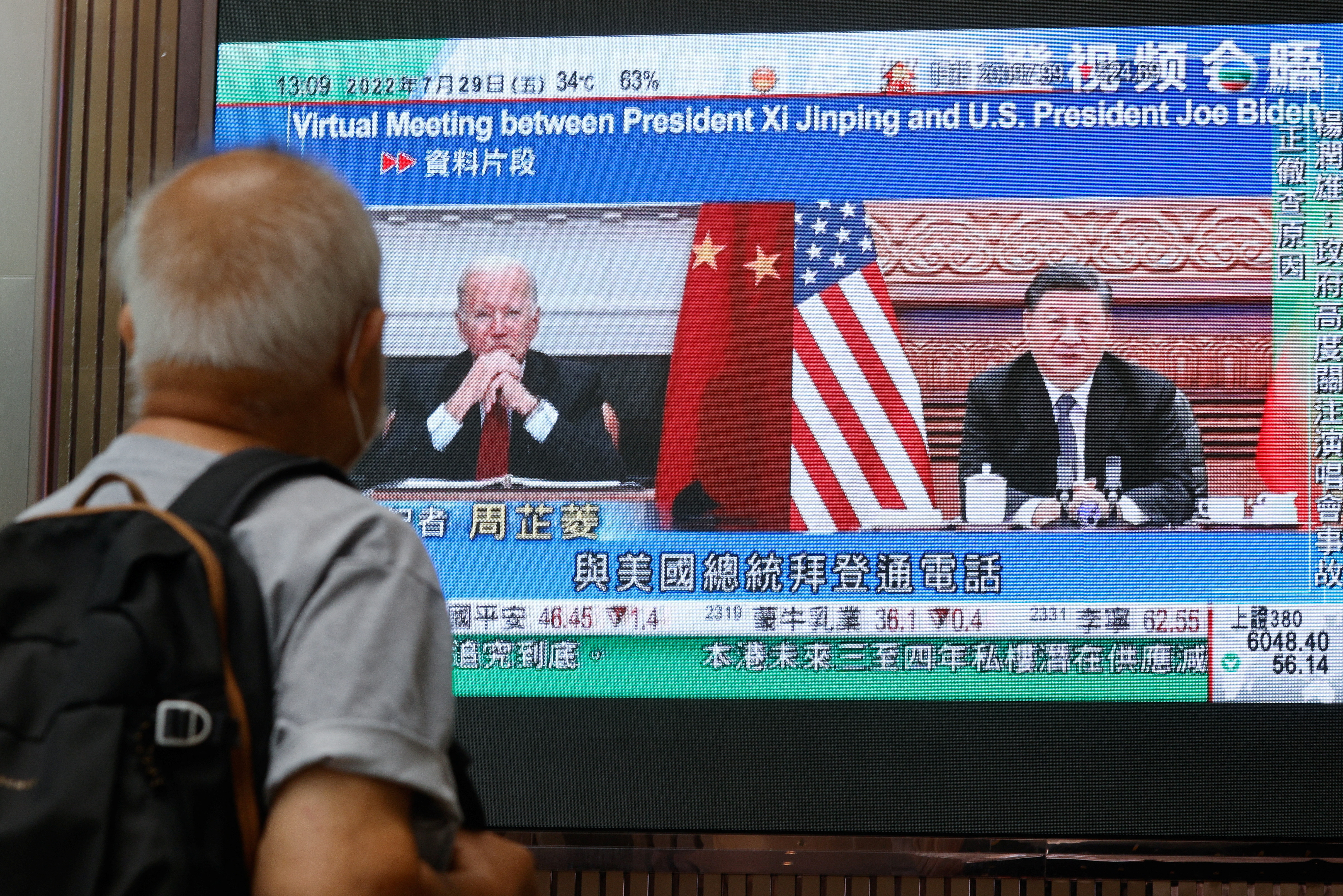 A screen displays images of Chinese President Xi Jinping and U.S. President Joe Biden, while broadcasting news about their recent call at a shopping mall in Hong Kong