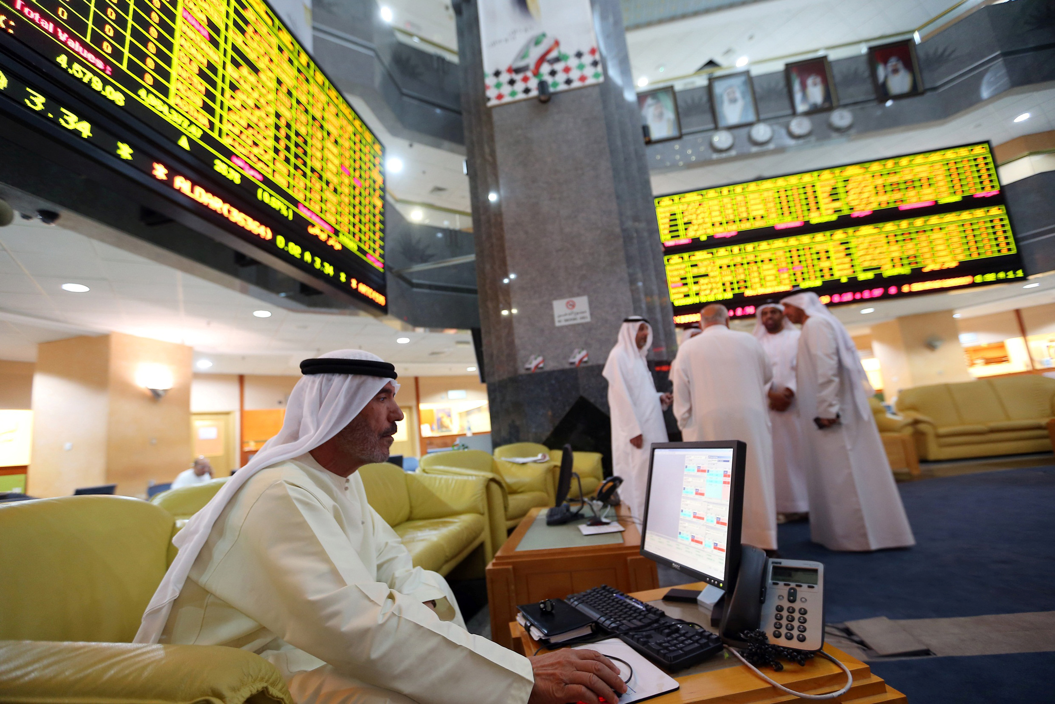 An investor monitors a screen displaying stock information at the Abu Dhabi Securities Exchange