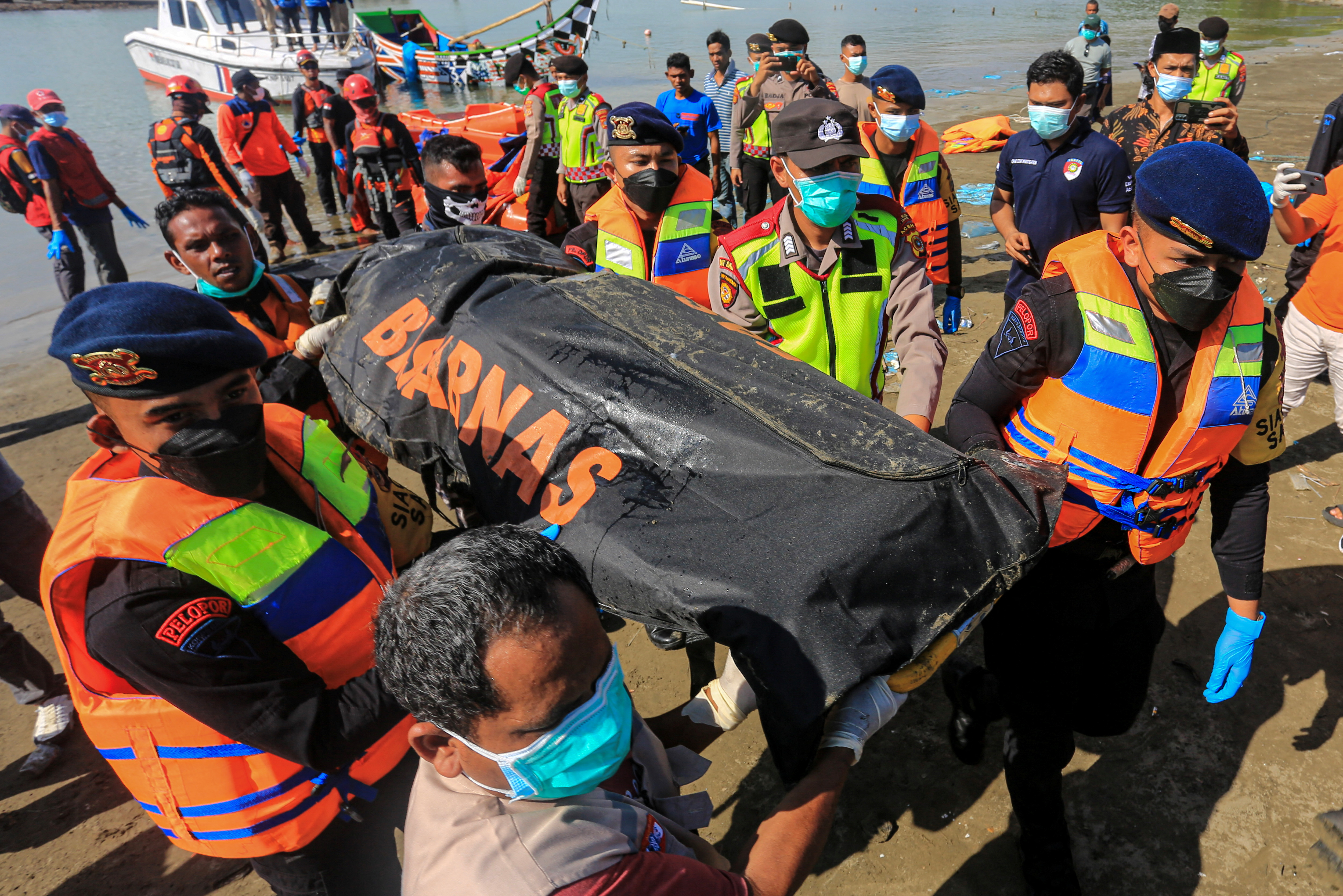 Rescuers carry body of Rohingya refugee recovered at sea after boat capsized off the coast near Calang