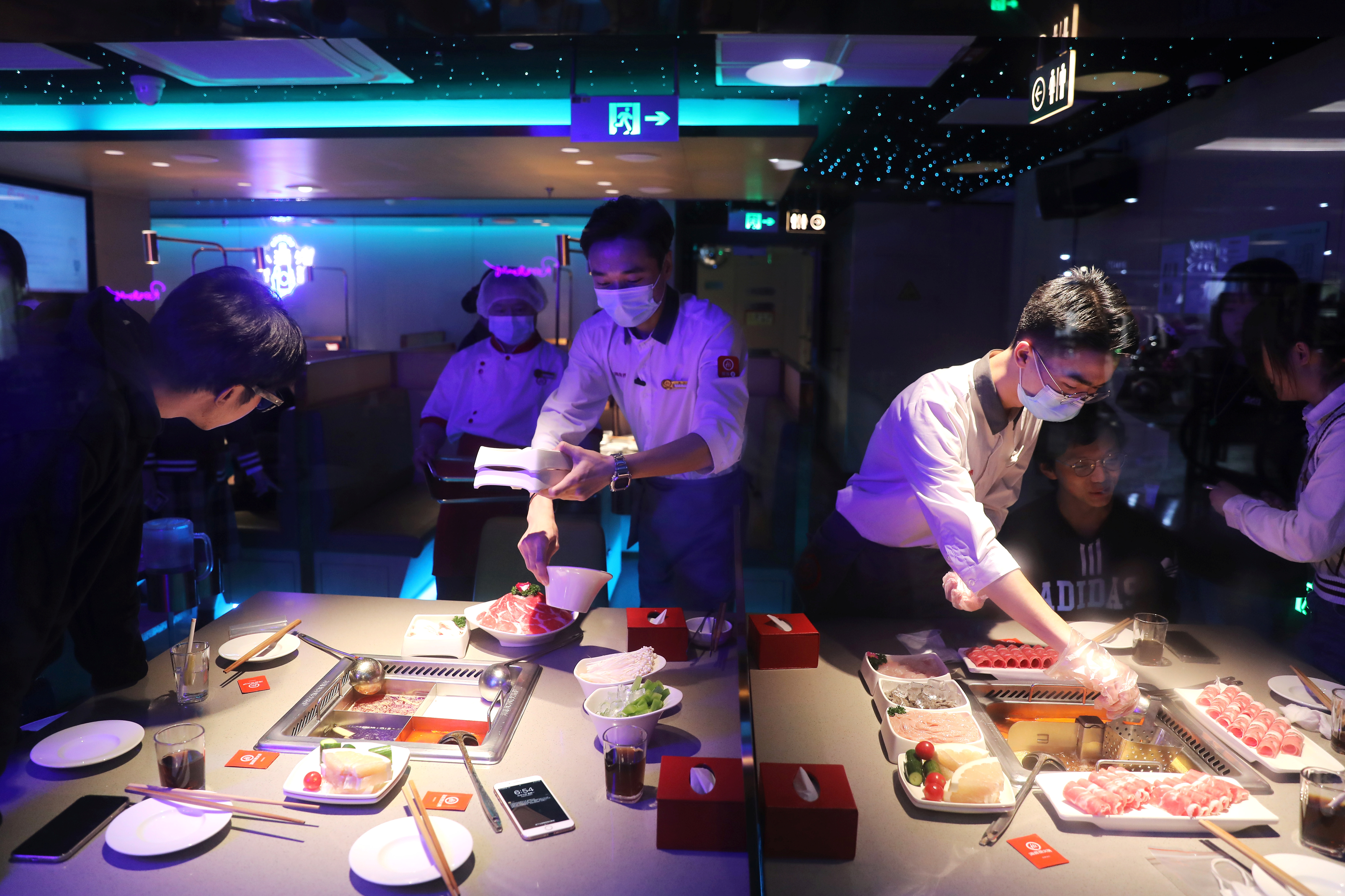 Waiters serve customers at a Haidilao hotpot restaurant in Beijing