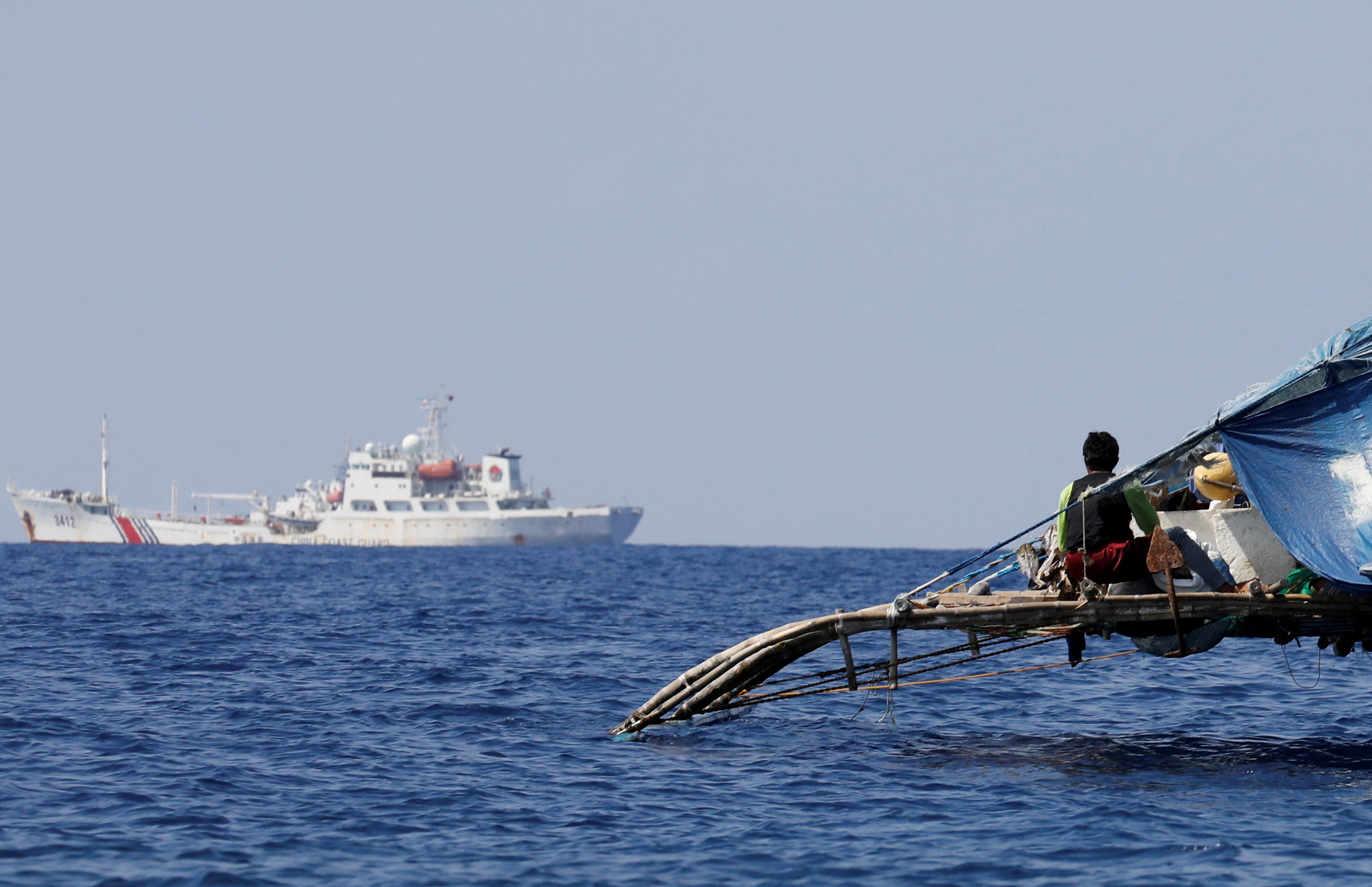 A Philippine fisherman watches a China Coast Guard vessel patrolling the disputed Scarborough Shoal