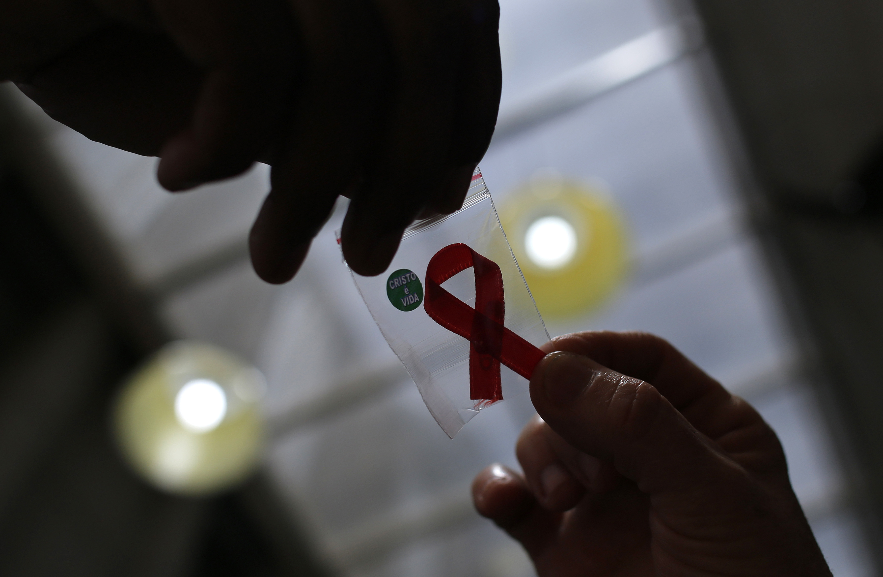 Nurse gives a red ribbon to a woman to mark World Aids Day at the entrance of Emilio Ribas Hospital, in Sao Paulo