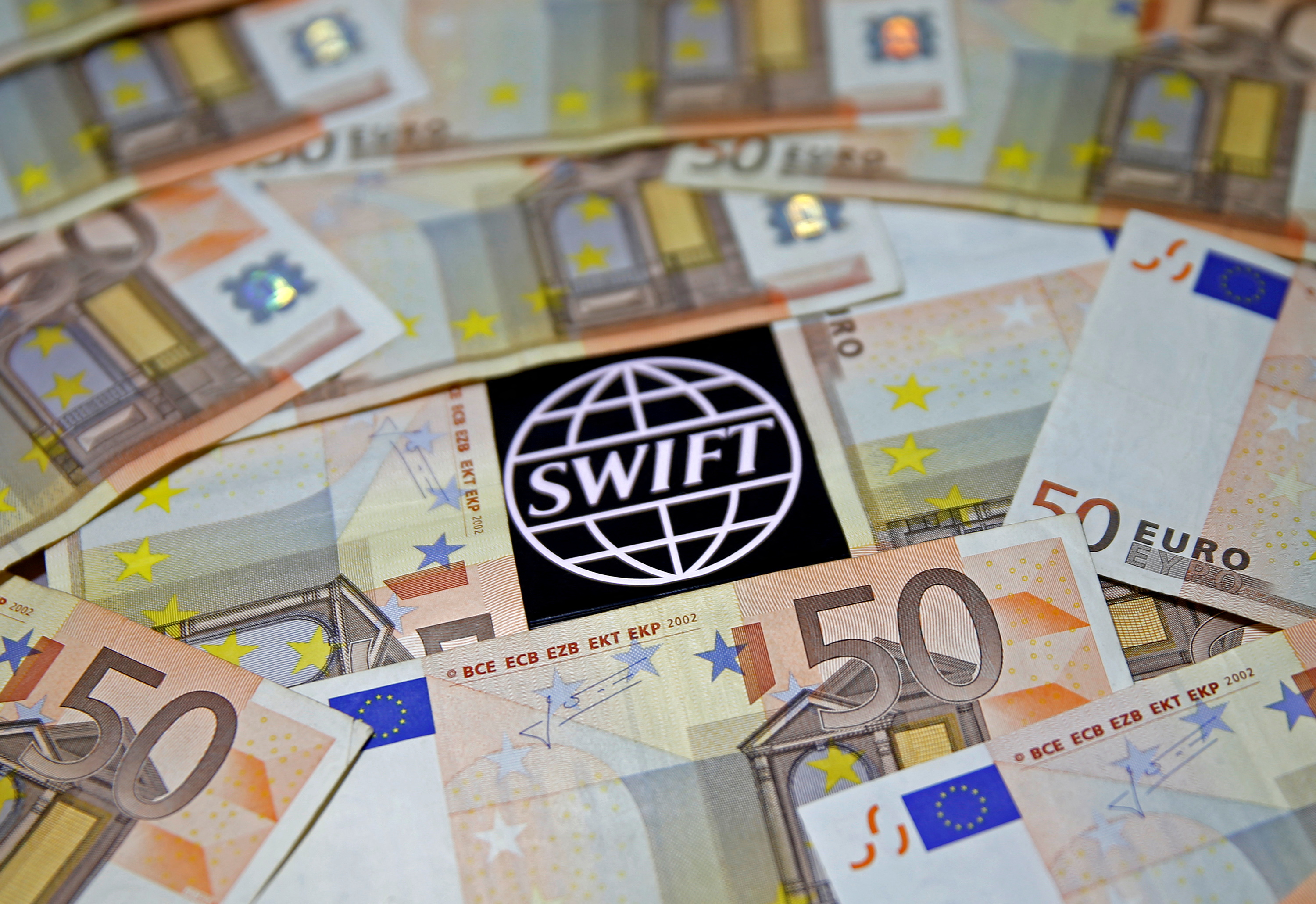 FILE PHOTO: Swift code bank logo is displayed on an iPhone 6s among Euro banknotes in this picture illustration