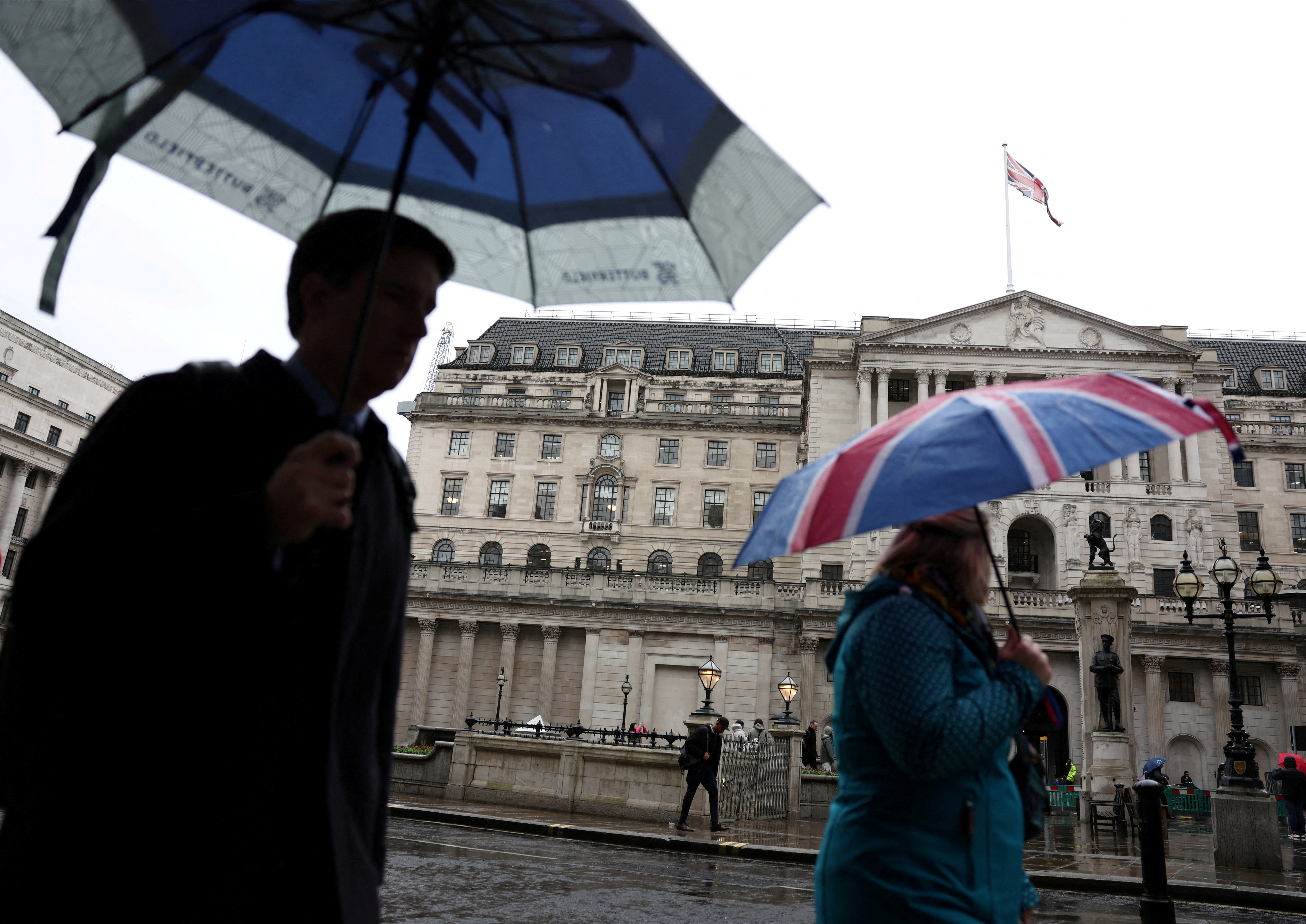 Tourists shelter from the rain under an Union Jack umbrella near the Bank of England in the City of London