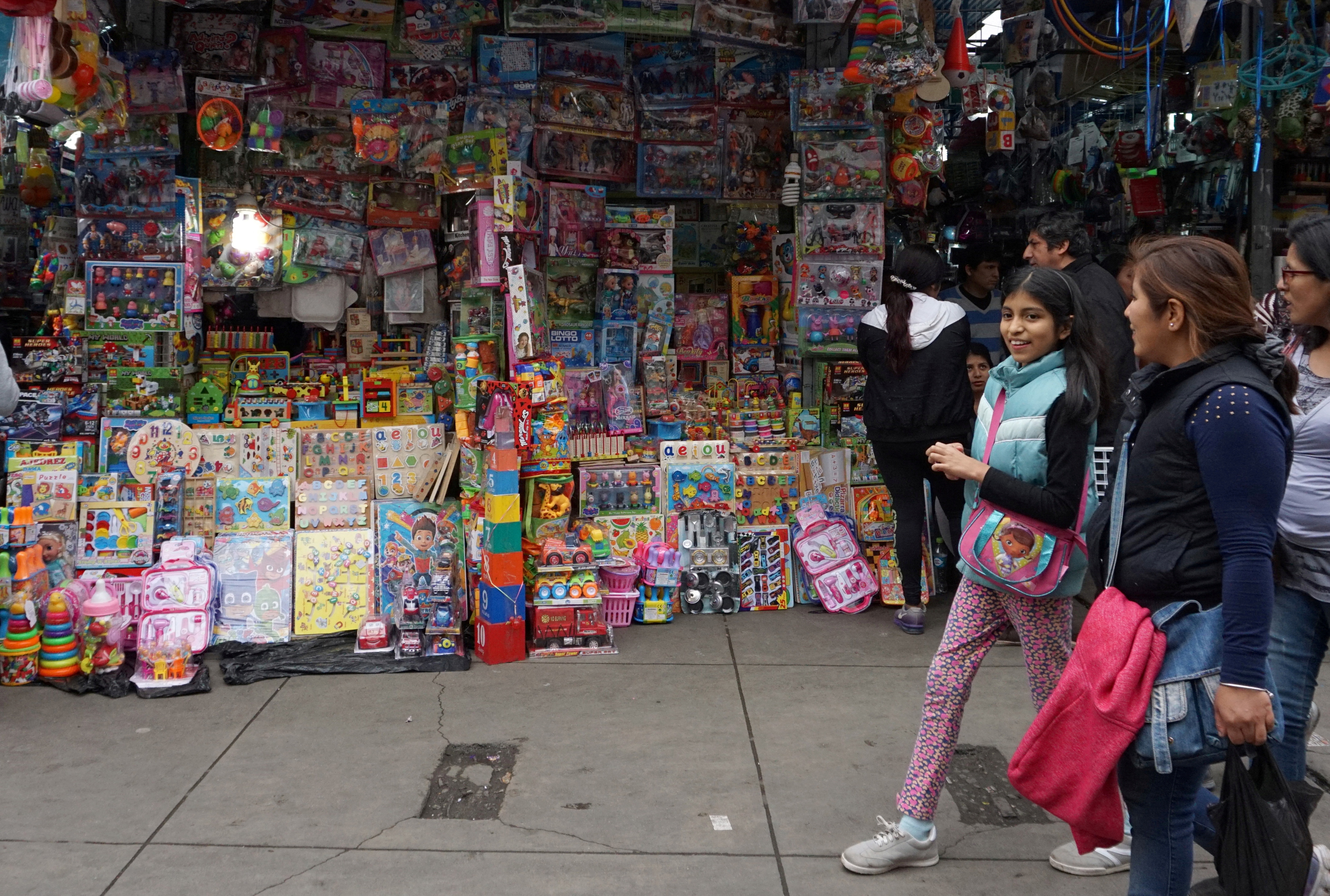People walk past a stand that sells toys and other products imported from China at Central Market in Lima