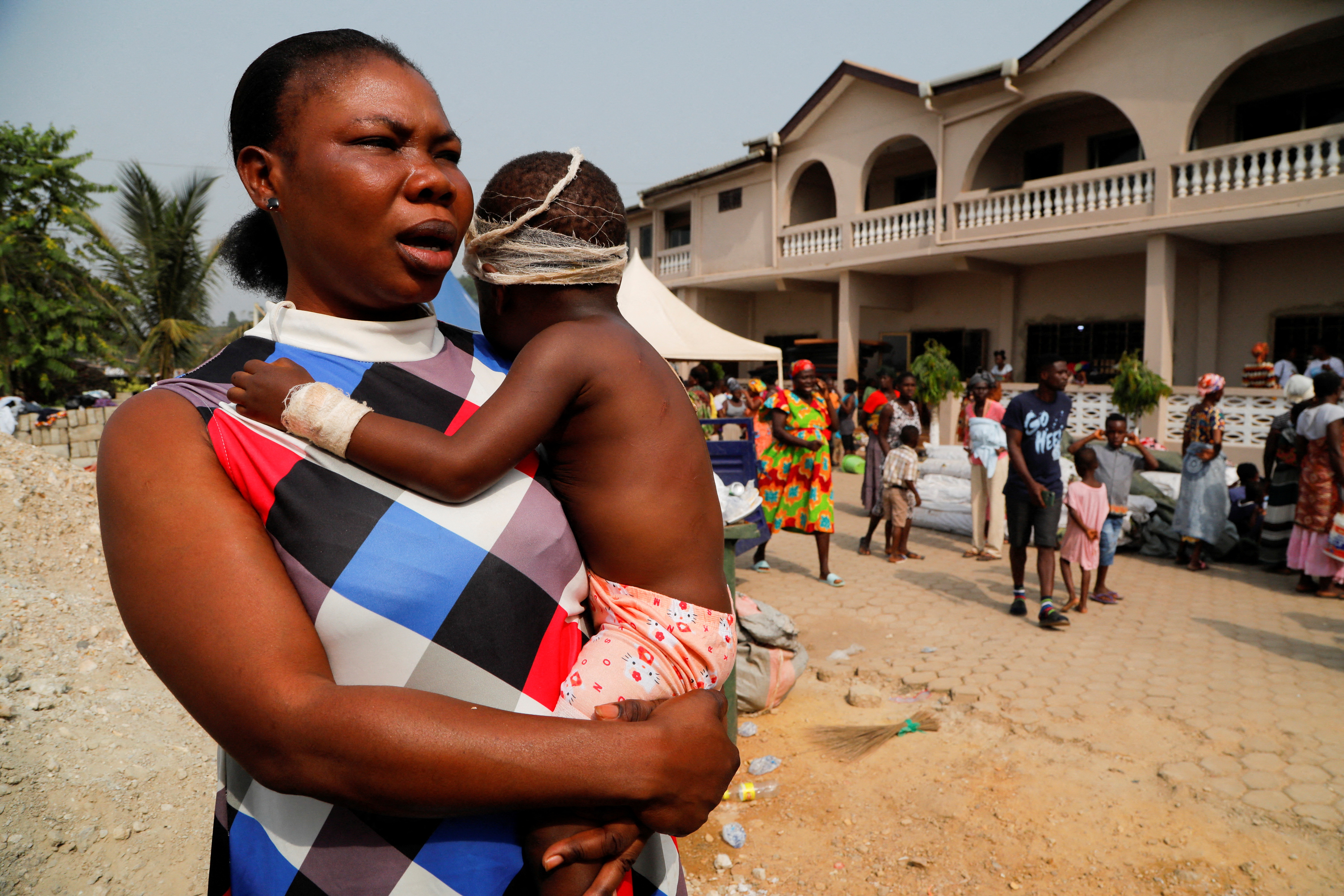 Anastasia Buckman, 36, carries her daughter, Juanita, 2, who suffered wounds when a vehicle carrying mining explosives detonated along a road in Apiate, in Bogoso