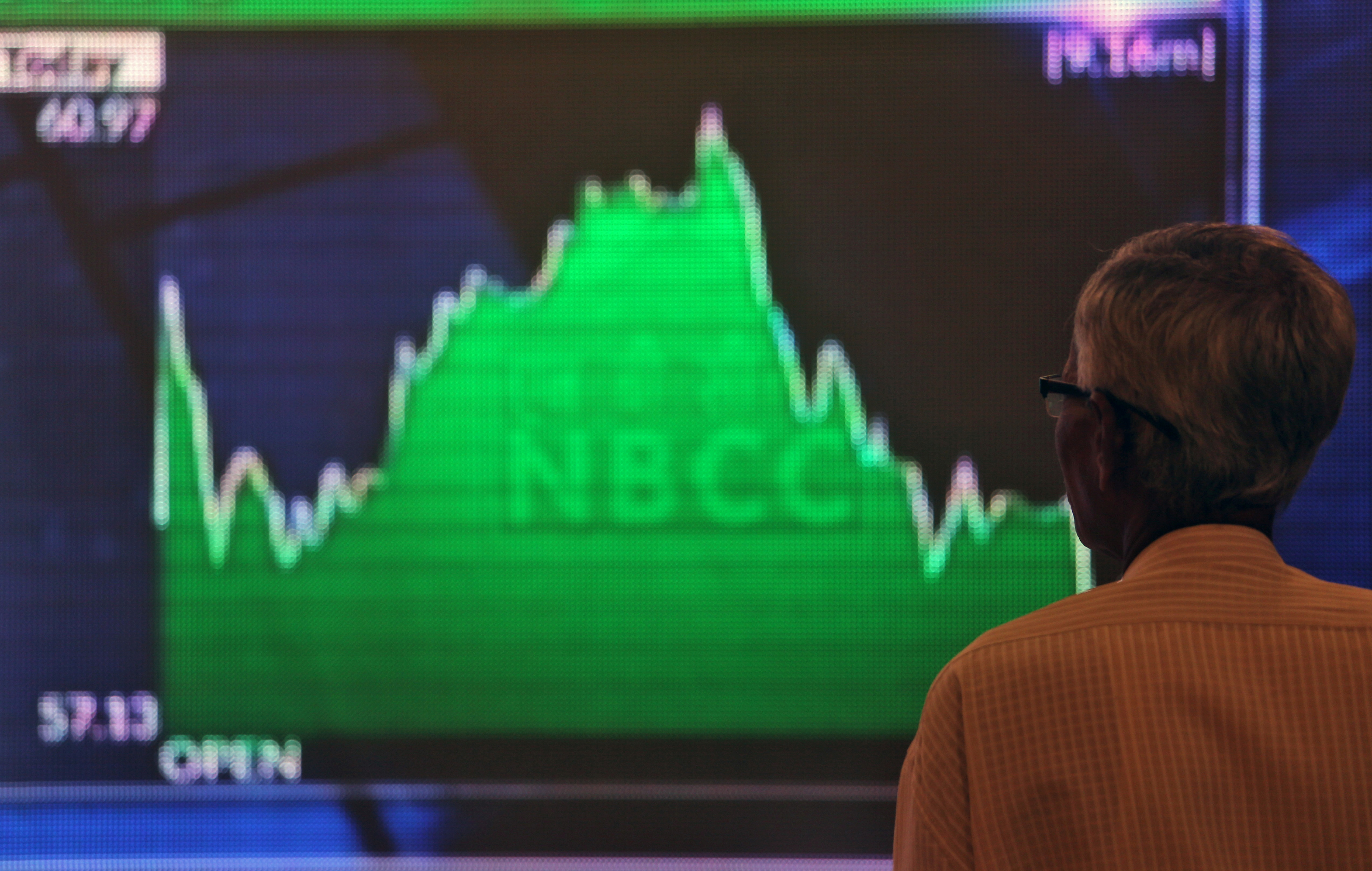 A man looks at a screen displaying news of markets update inside the Bombay Stock Exchange (BSE) building in Mumbai