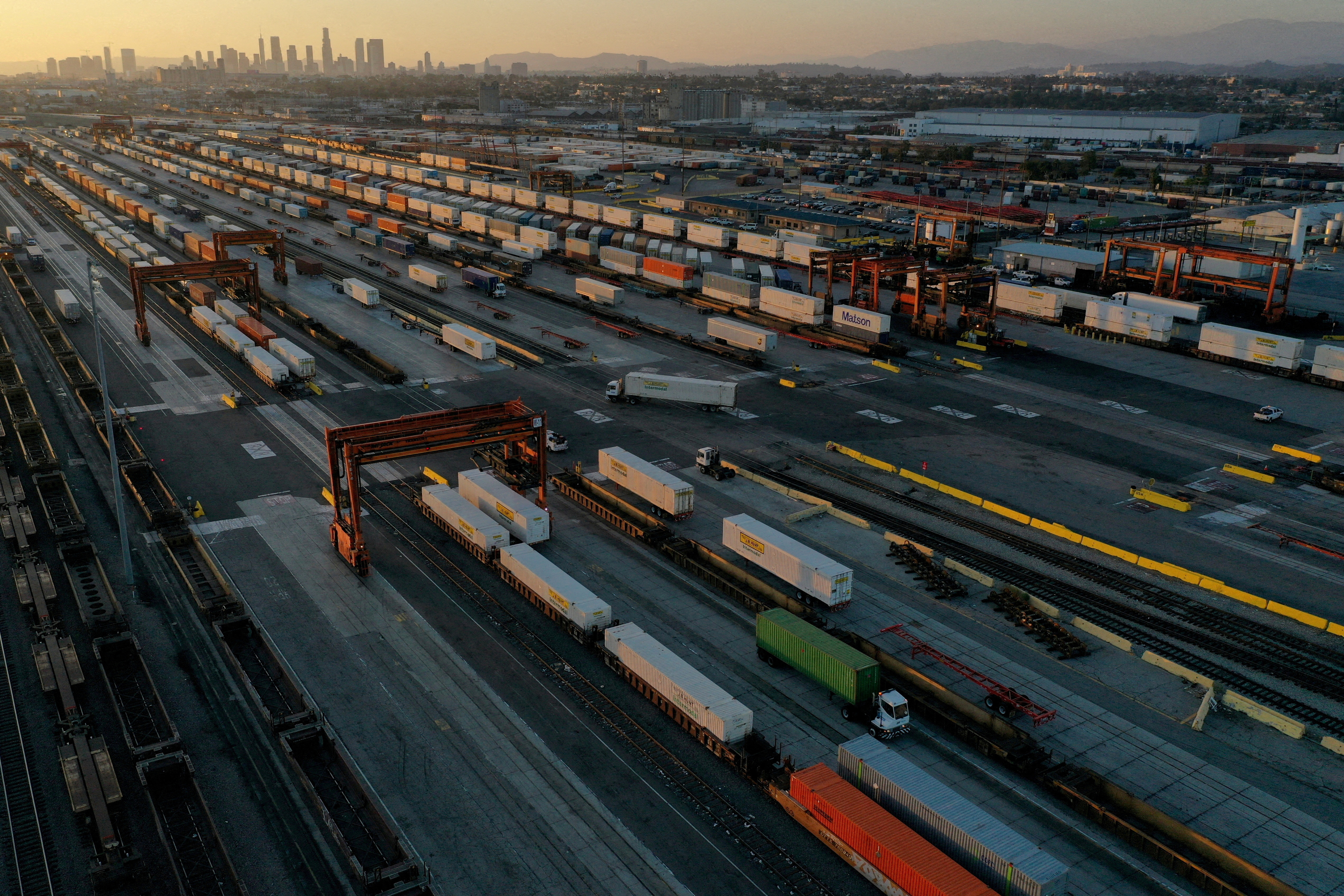 An aerial view of gantry cranes, shipping containers, and freight railway trains  in Commerce