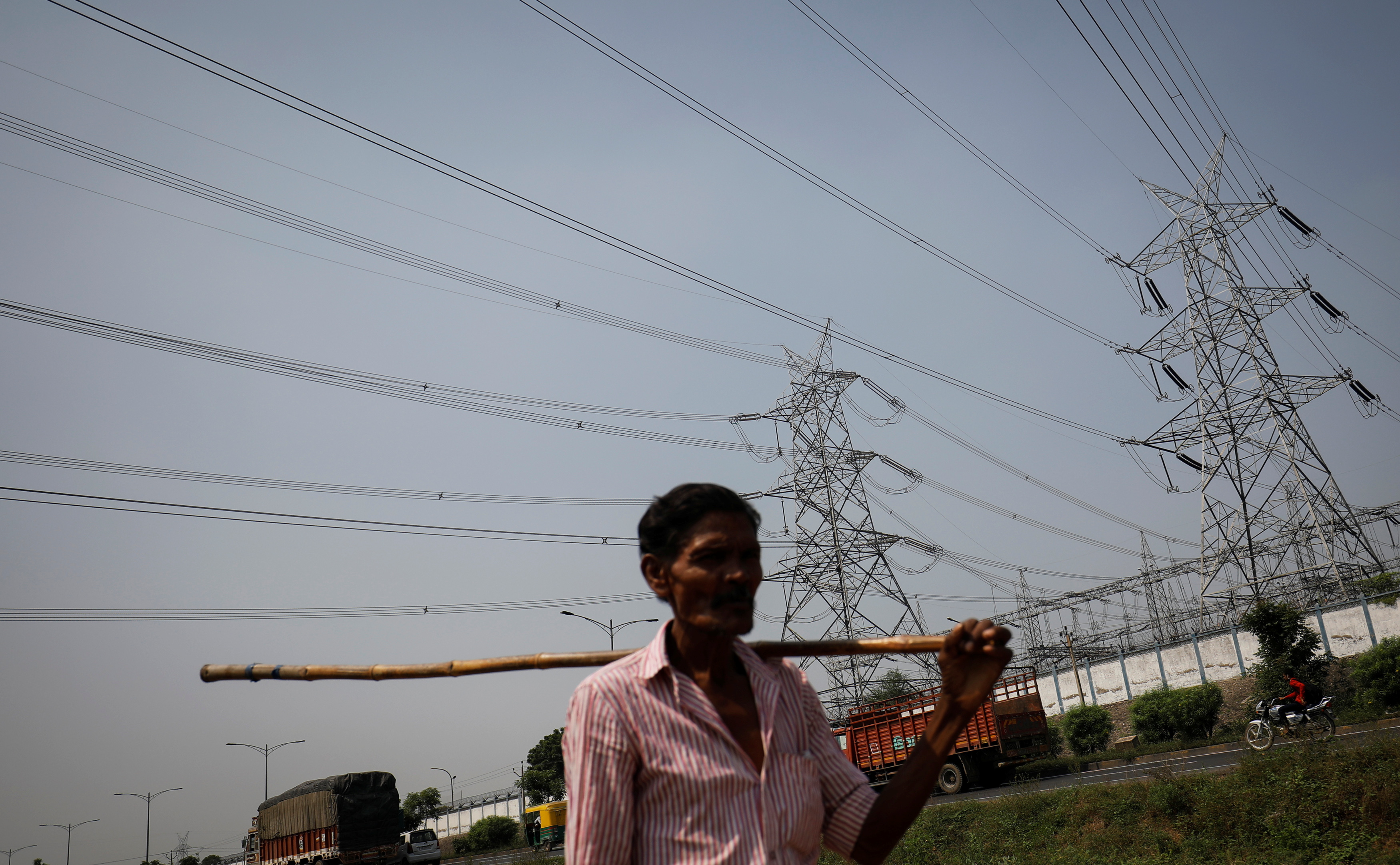 Man walks past electricity pylons on the outskirts of Ahmedabad
