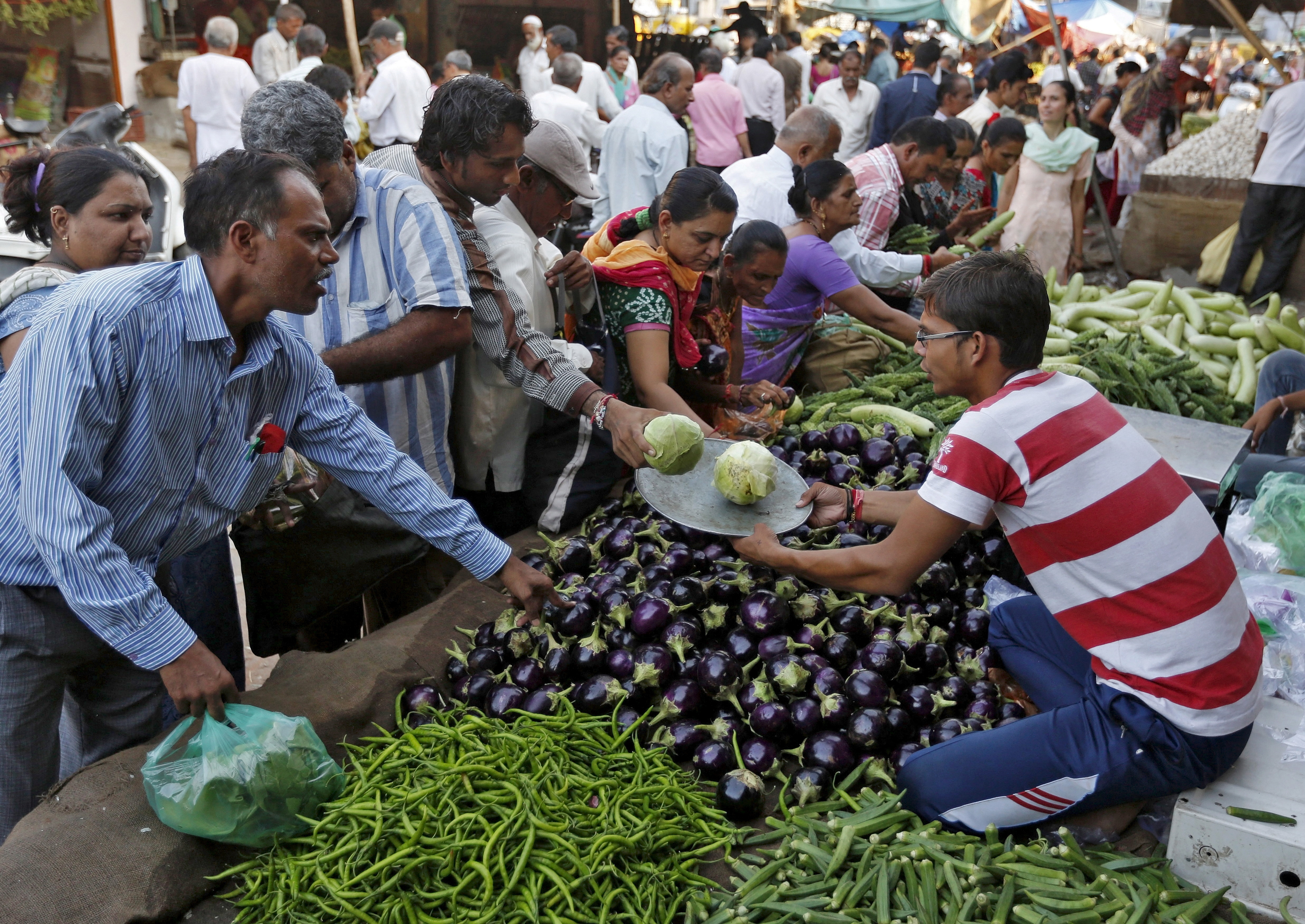 Customers buy vegetables at a market in Ahmedabad