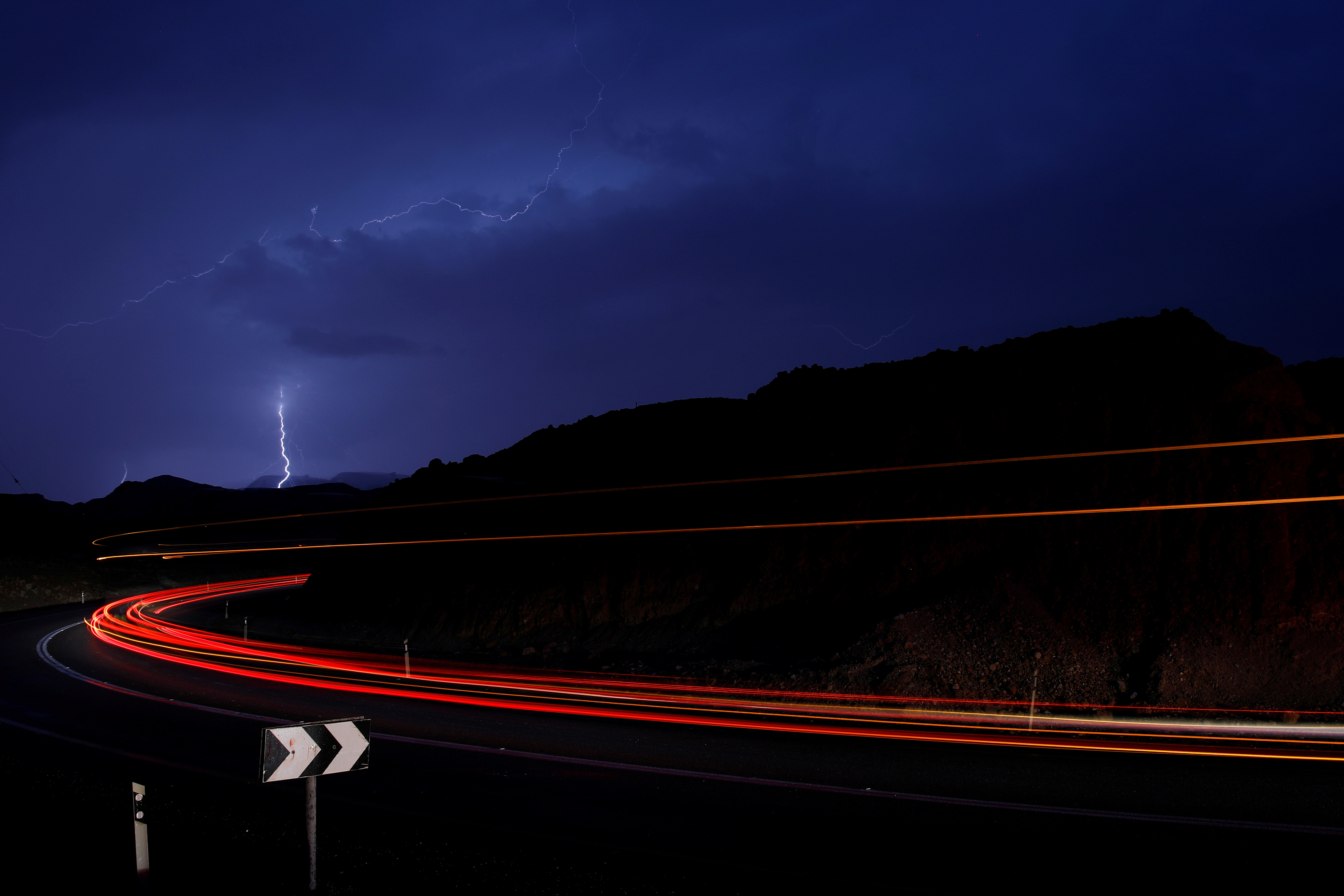 Cars drive as lightning strikes near the site where a group of Israeli youths was swept away by a flash flood, near the Zafit river bed, south to the Dead Sea