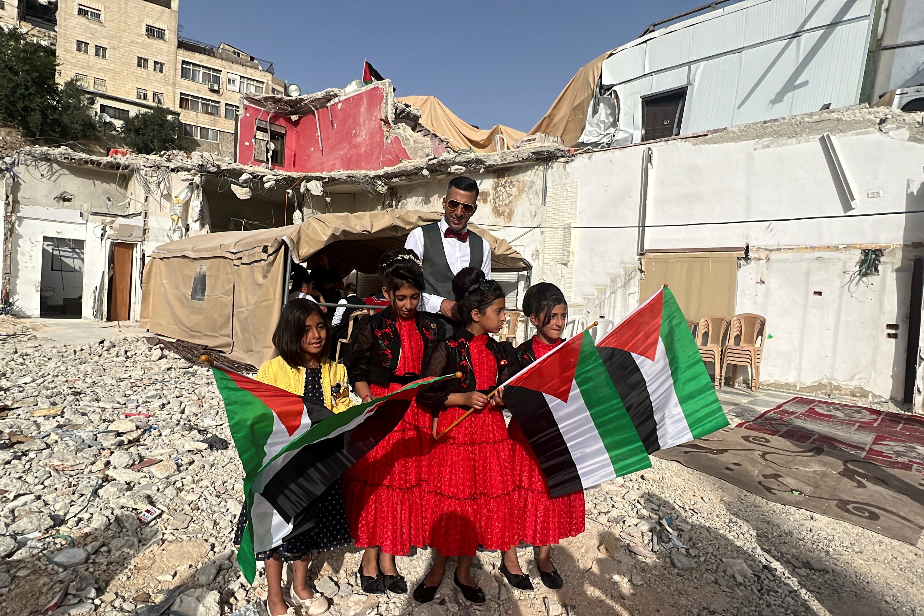 Feras, brother of a Palestinian bride Rabeha Al-Rajabi, stands together with girls during a pre-wedding ceremony at the family's house, that was partly demolished by Israel authority, in East Jerusalem