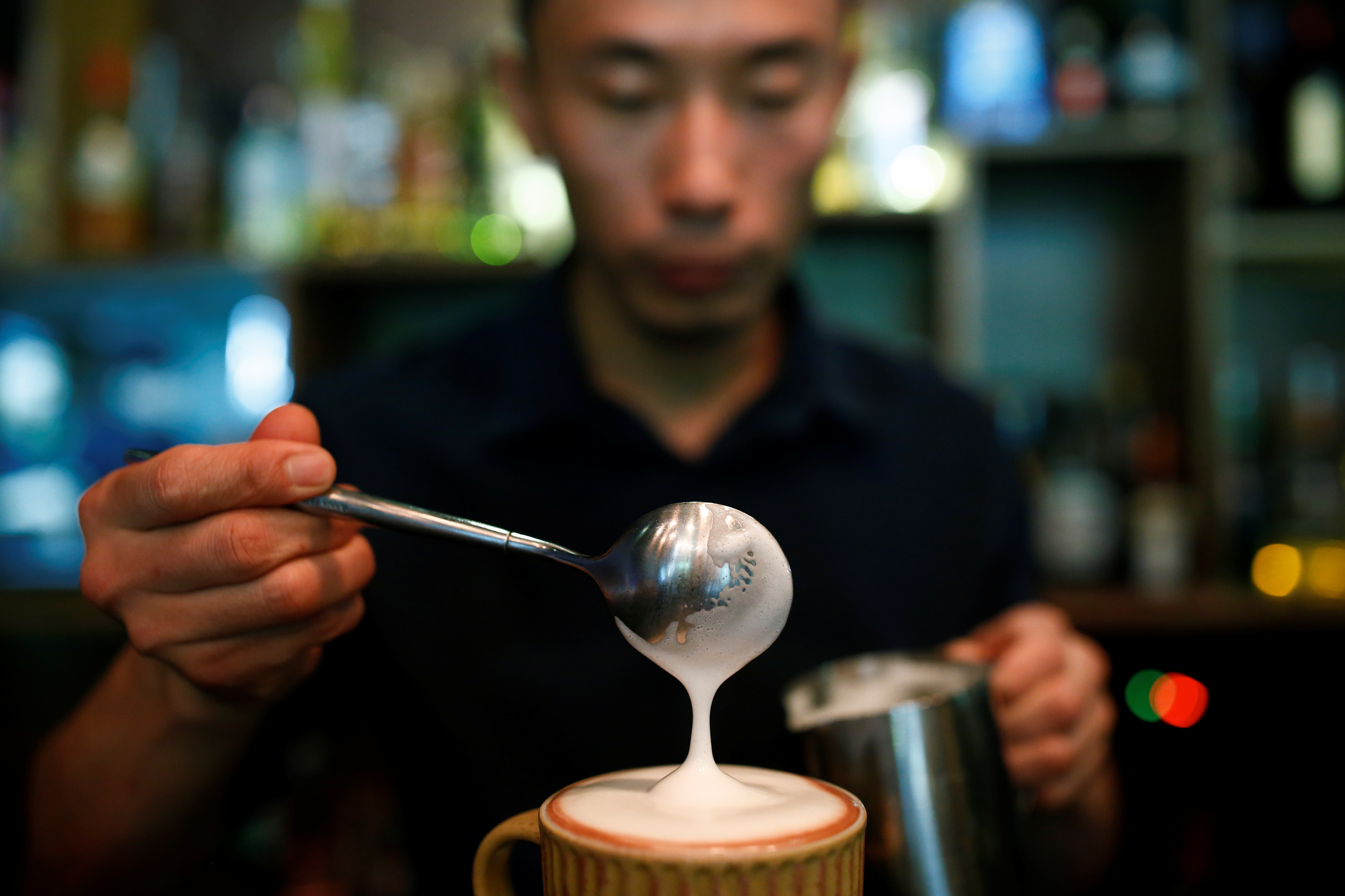 A barista pours milk into a coffee at the La Tercera cafe in Beijing