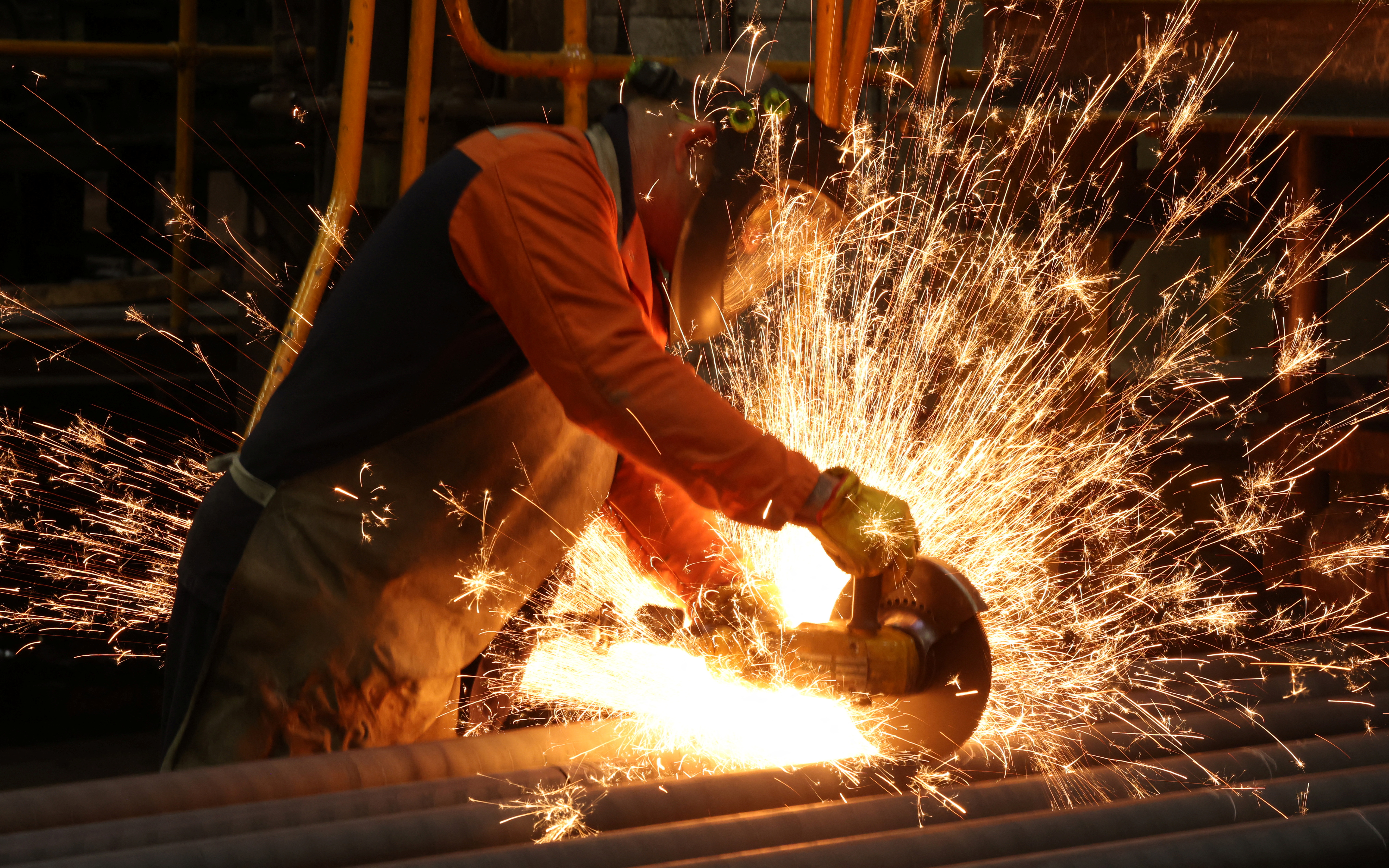 A worker cuts newly manufactured bars of steel at the United Cast Bar Group's foundry in Chesterfield