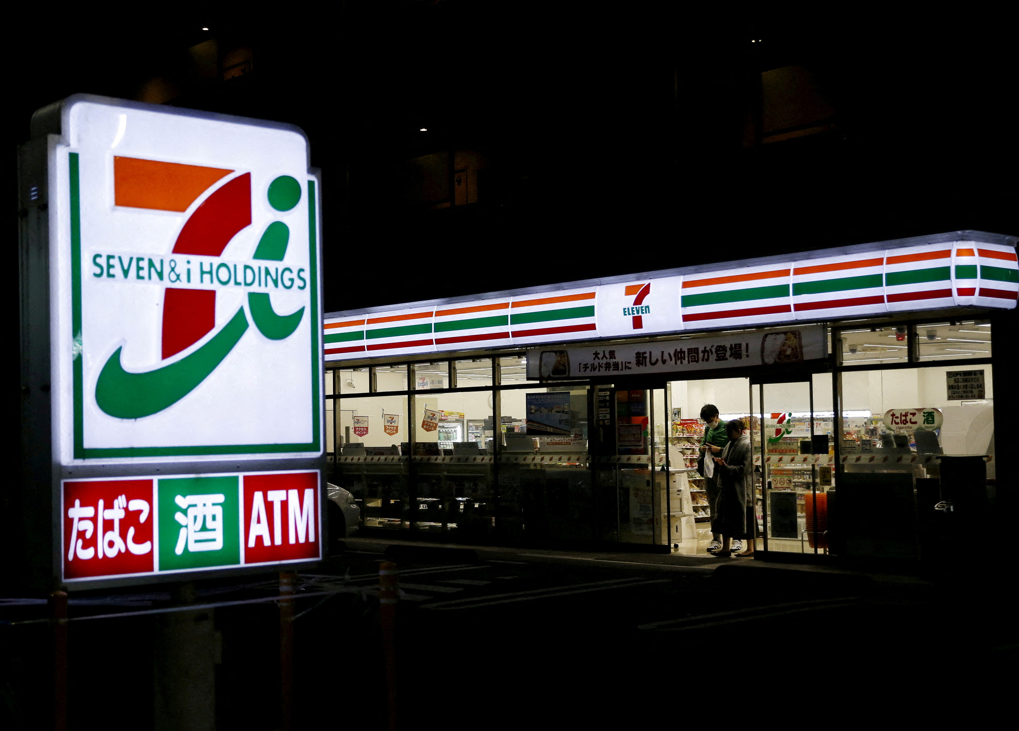 Shoppers walk out from a 7-Eleven convenience store in Tokyo