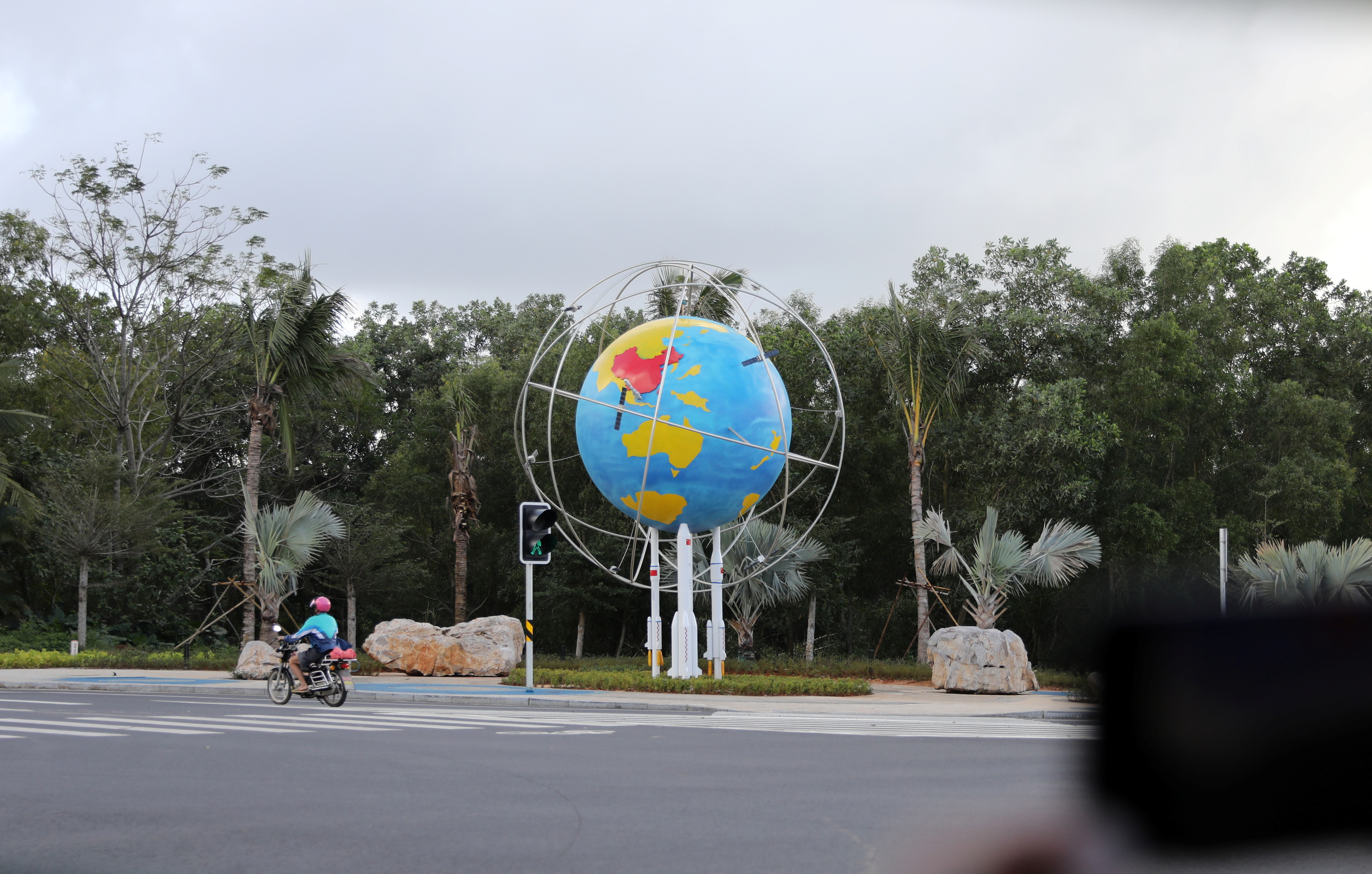 A motorcyclist passes a model of Planet Earth at a space science museum in Wenchang, Hainan