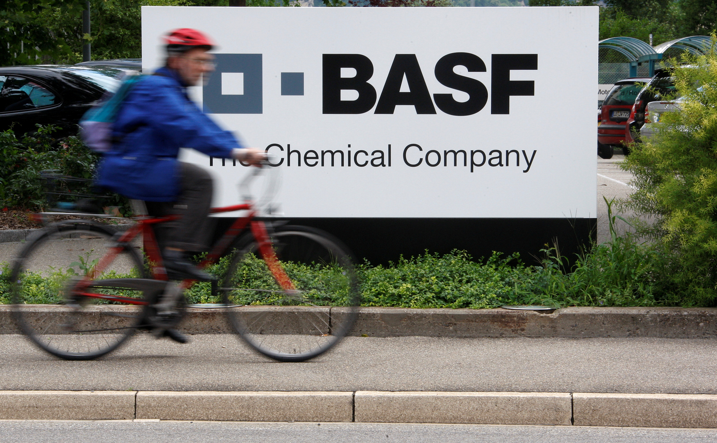 A cyclist rides past the entrance of a BASF plant in Schweizerhalle near Basel, Switzerland, July 7, 2009.  REUTERS/Christian Hartmann