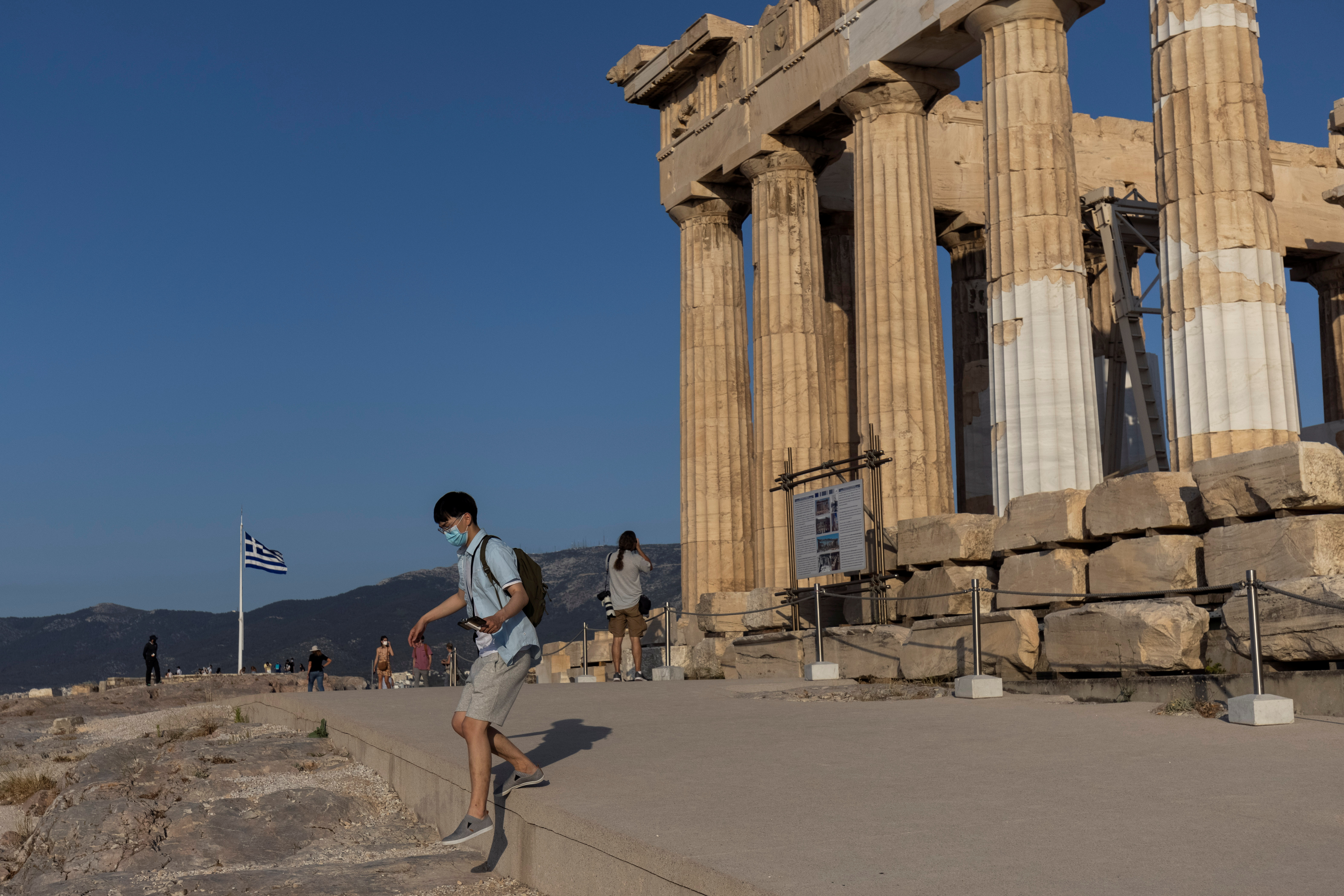 A man steps off a new cement walkway next to the Parthenon temple, built to improve access for people with disabilities atop the Acropolis hill, in Athens