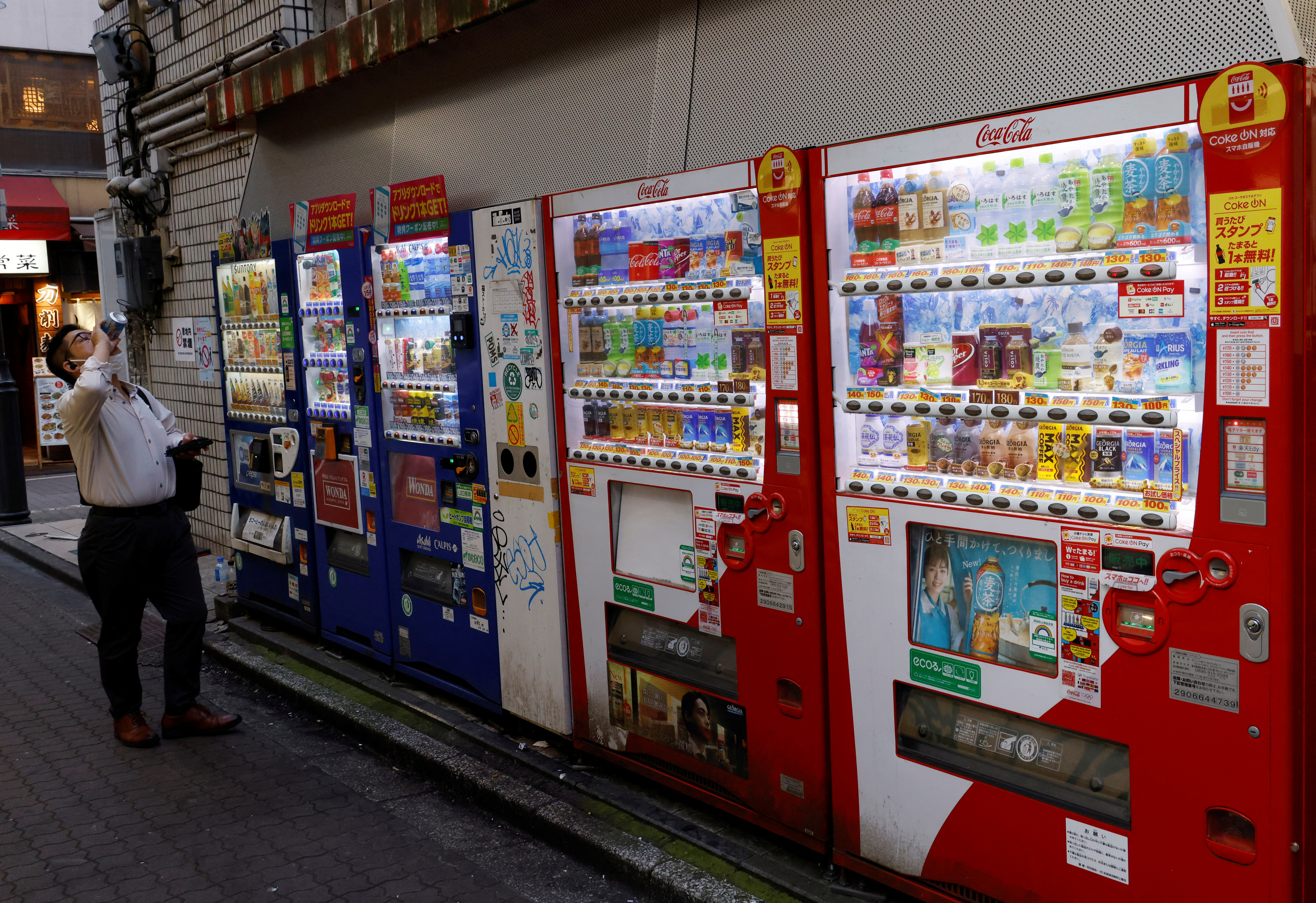 A man drinks beverage which he purchased from a vending machine in Tokyo