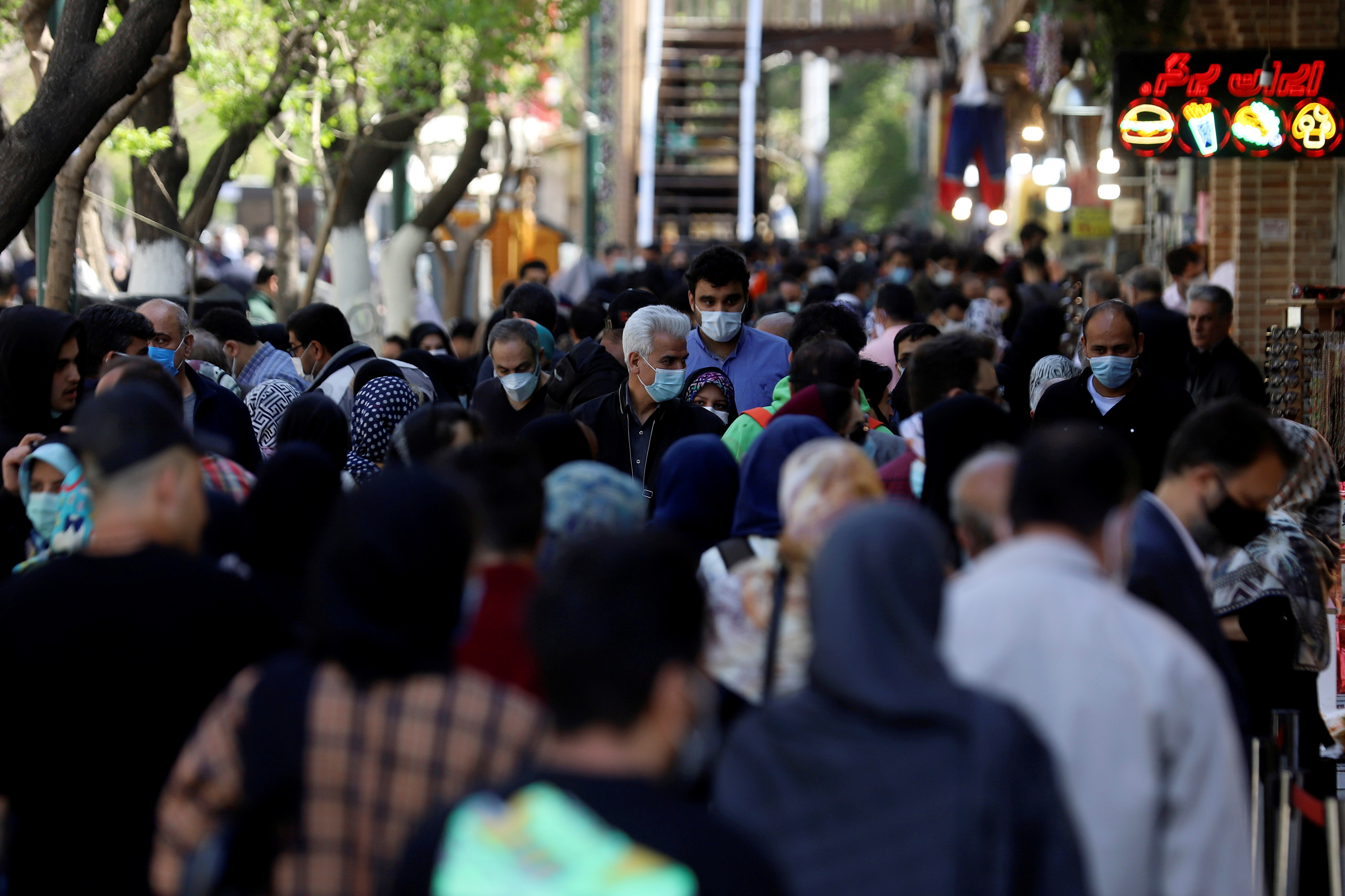 Iranians wearing protective face masks against the coronavirus walk in a crowded area of the capital Tehran, Iran