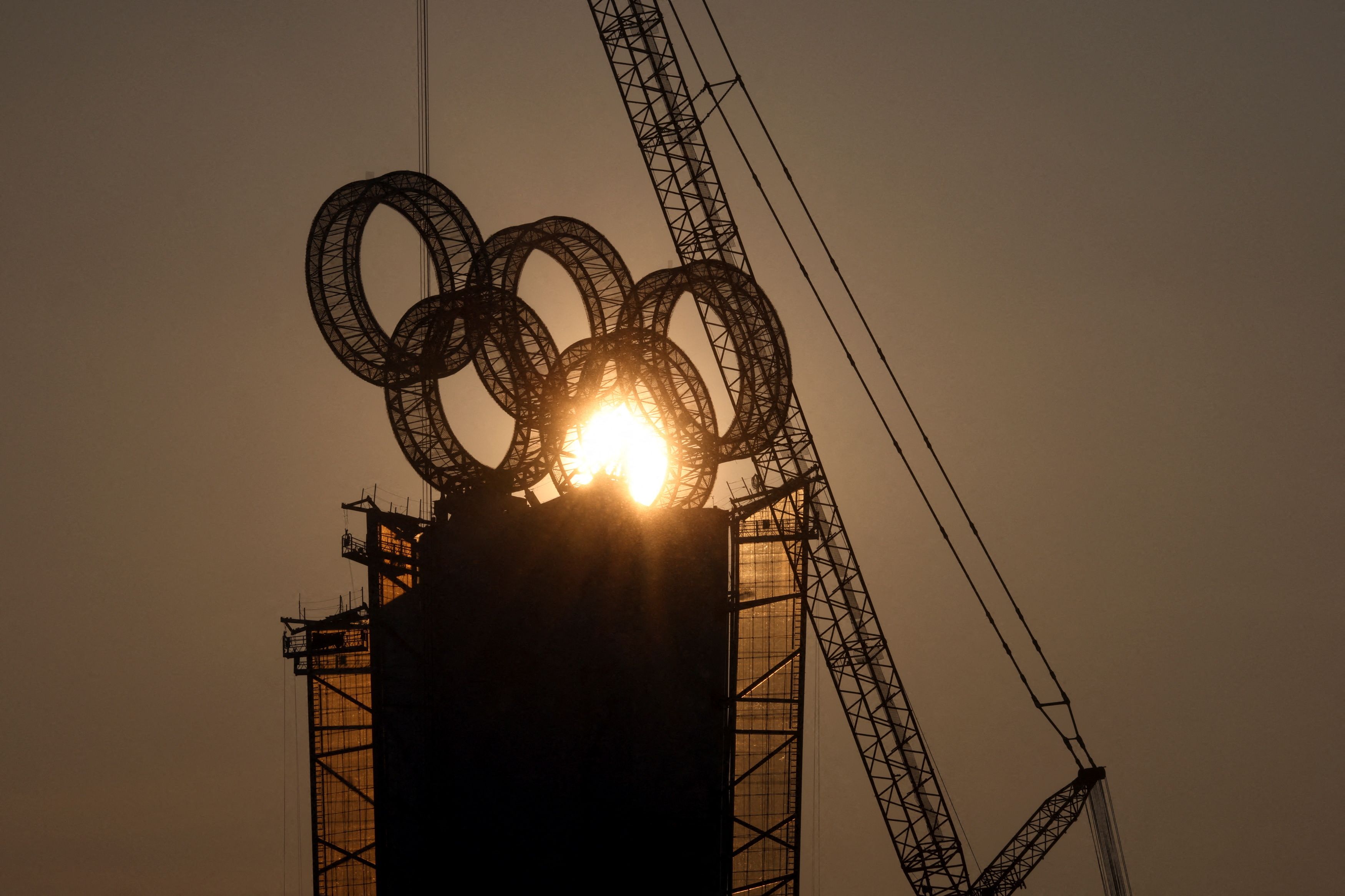 The sun sets behind the Olympic Rings atop a tower near the Yanqing cluster of Beijing 2022 Winter Olympics, in Beijing