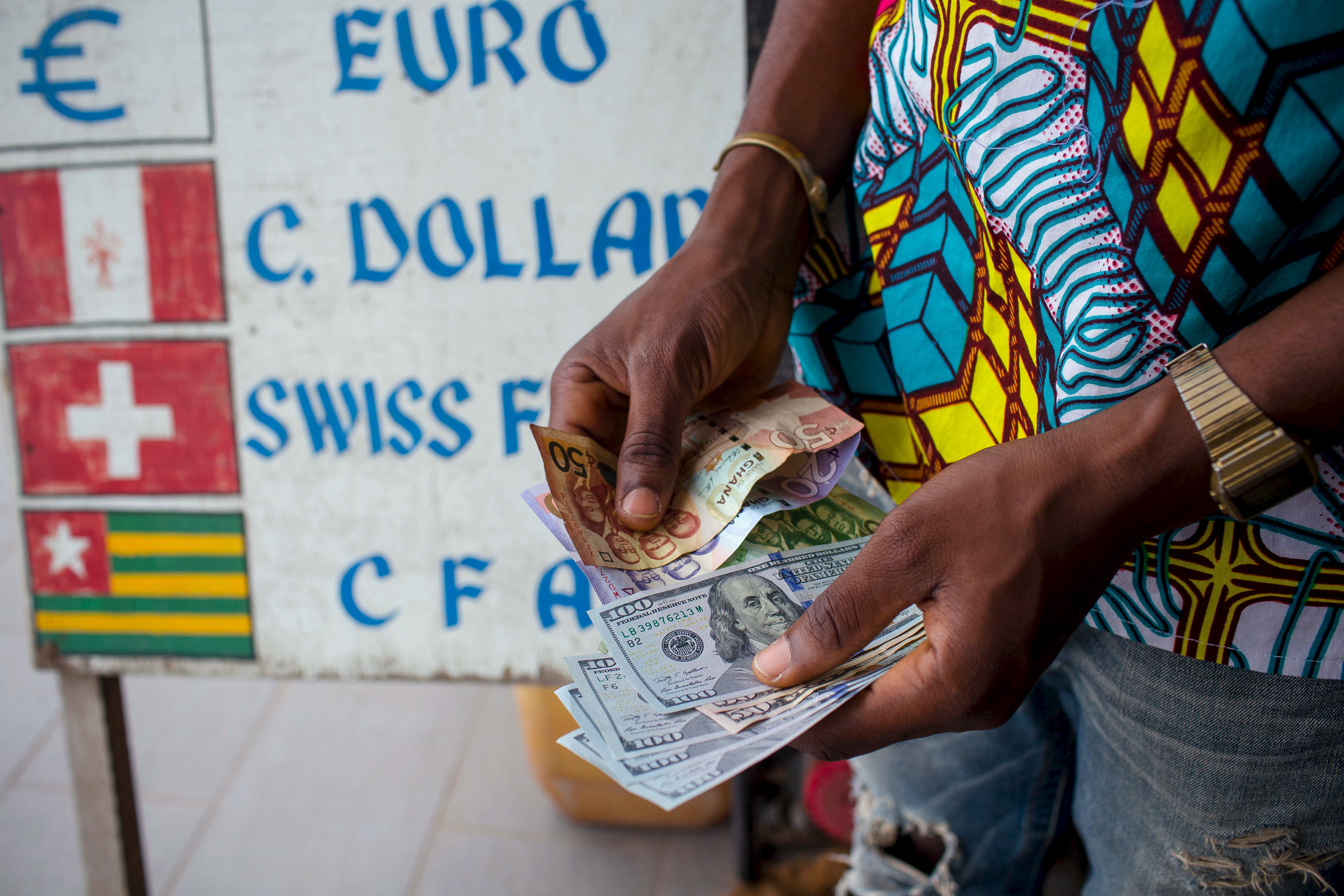 Man trades U.S. dollars for Ghanaian cedis at a currency exchange office in Accra