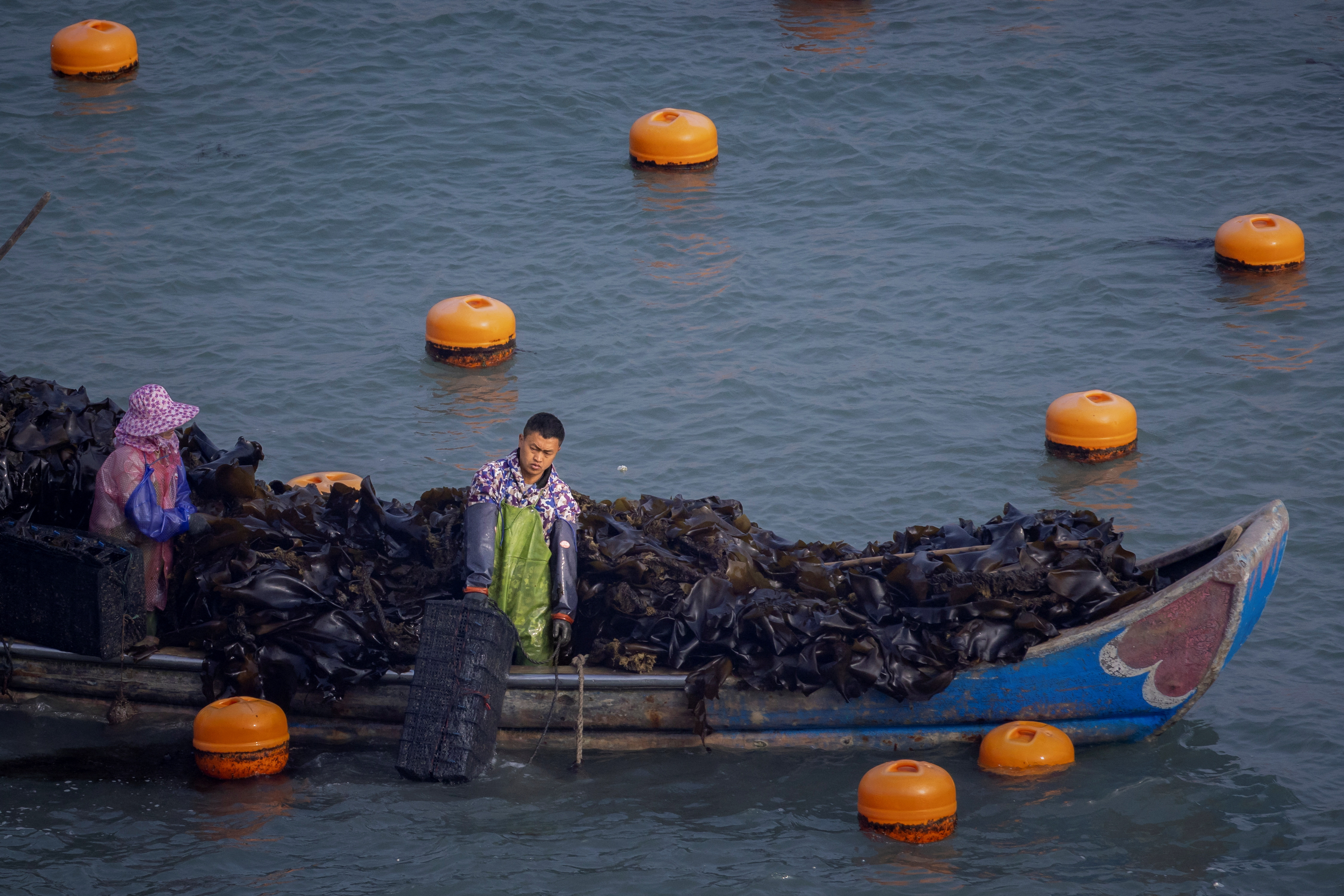 Fisherman standing on platform of Chinese net observing calm water