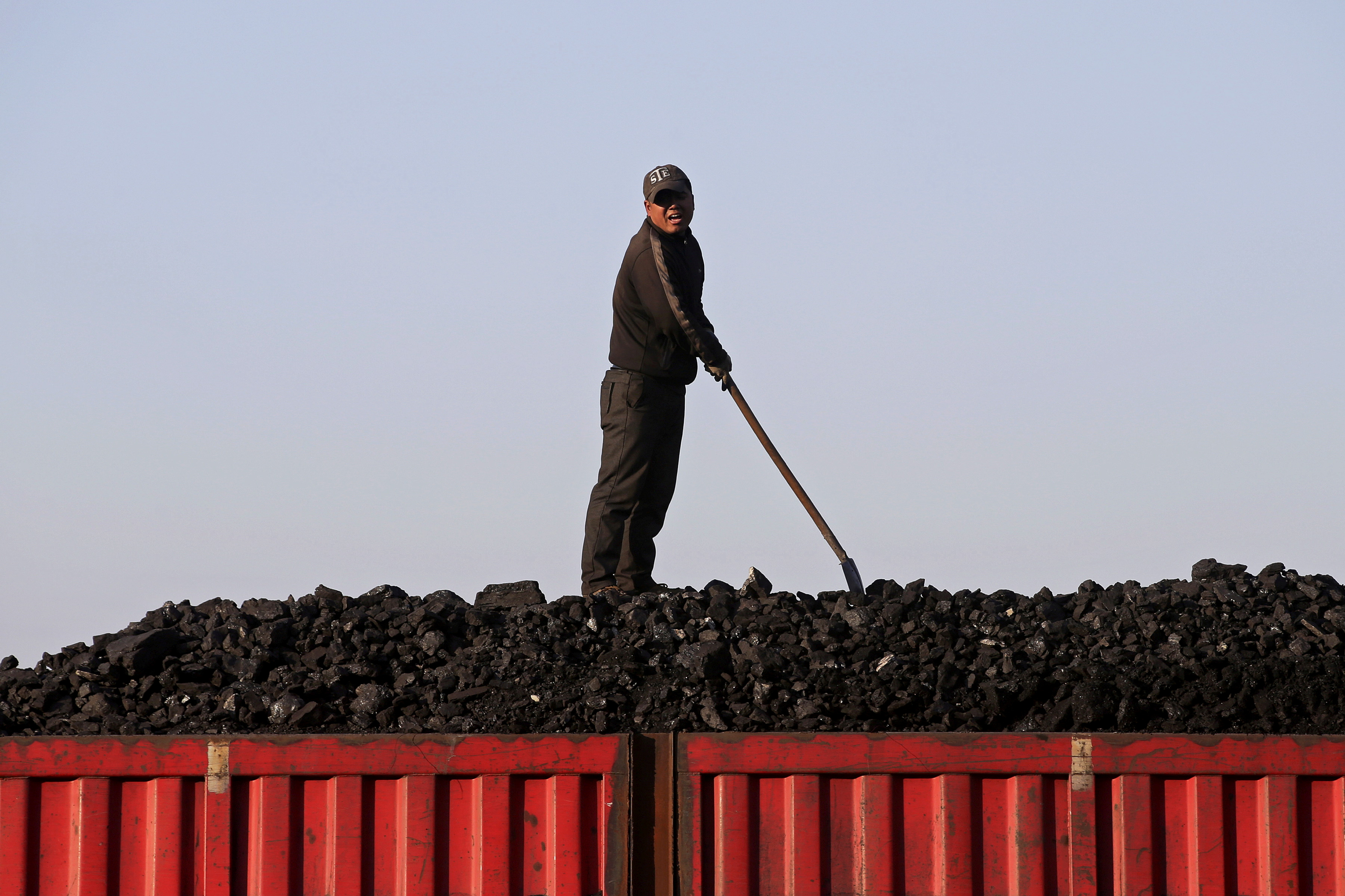 A worker speaks as he loads coal on a truck at a depot near a coal mine from the state-owned Longmay Group on the outskirts of Jixi, Heilongjiang, China