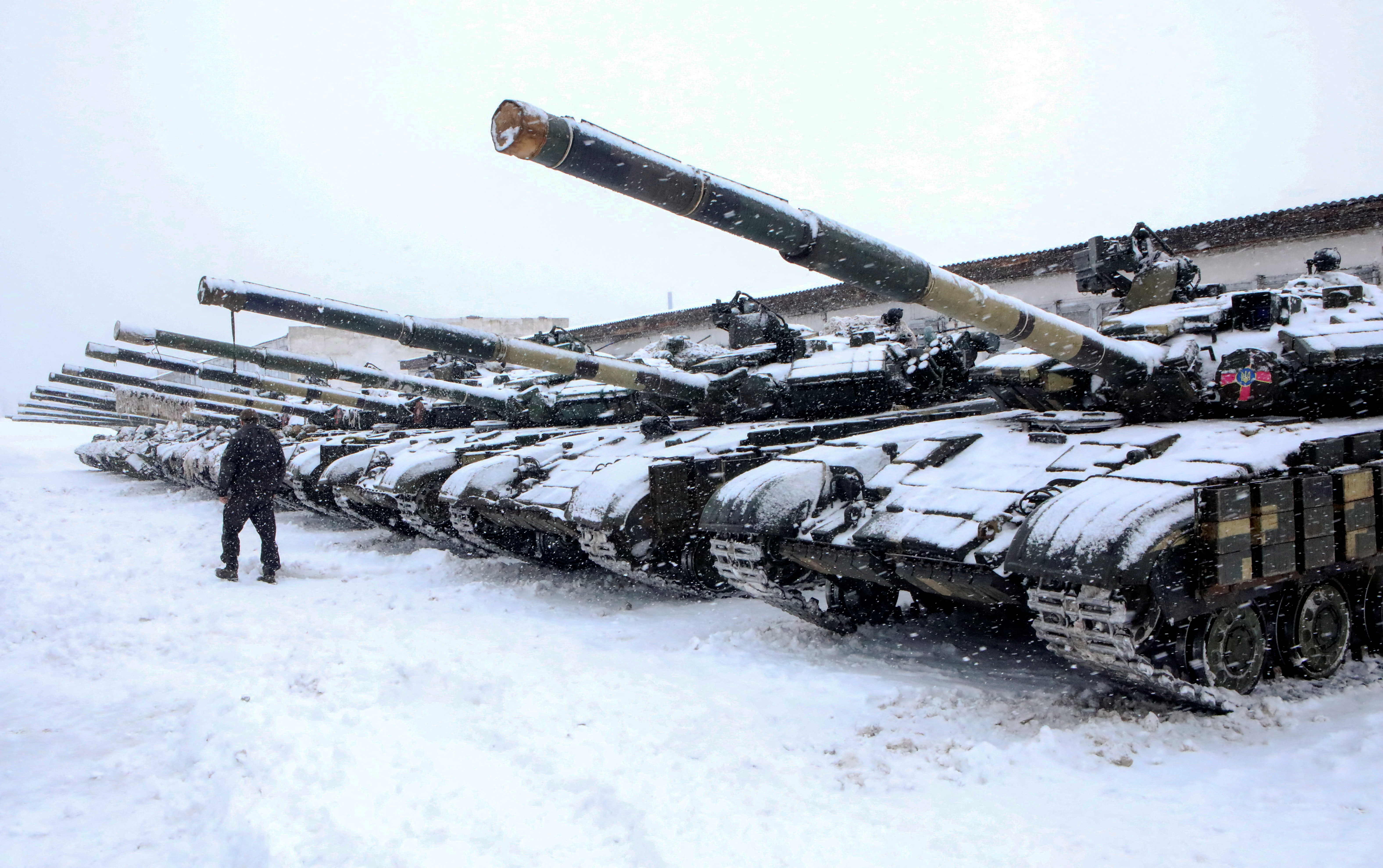 31 Ocak 2022, Ukrayna, Kharkiv dışındaki askeri tatbikatlar sırasında bir asker, Ukrayna Silahlı Kuvvetlerinin mekanize tugayının tanklarının yanından geçiyor. REUTERS/Vyacheslav Madiyevskyy