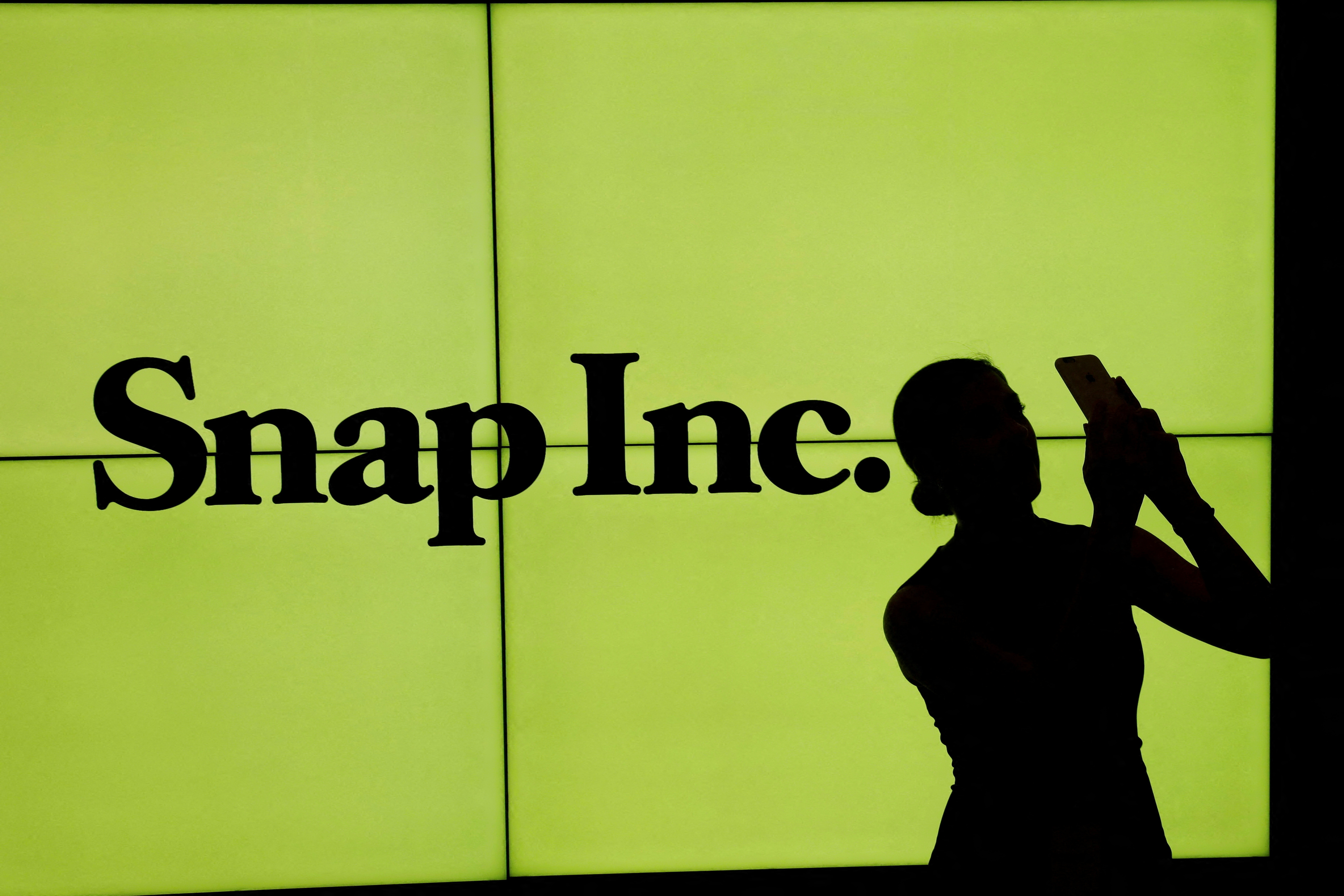Una mujer se para frente al logotipo de Snap Inc en el piso de la Bolsa de Valores de Nueva York (NYSE) en la ciudad de Nueva York