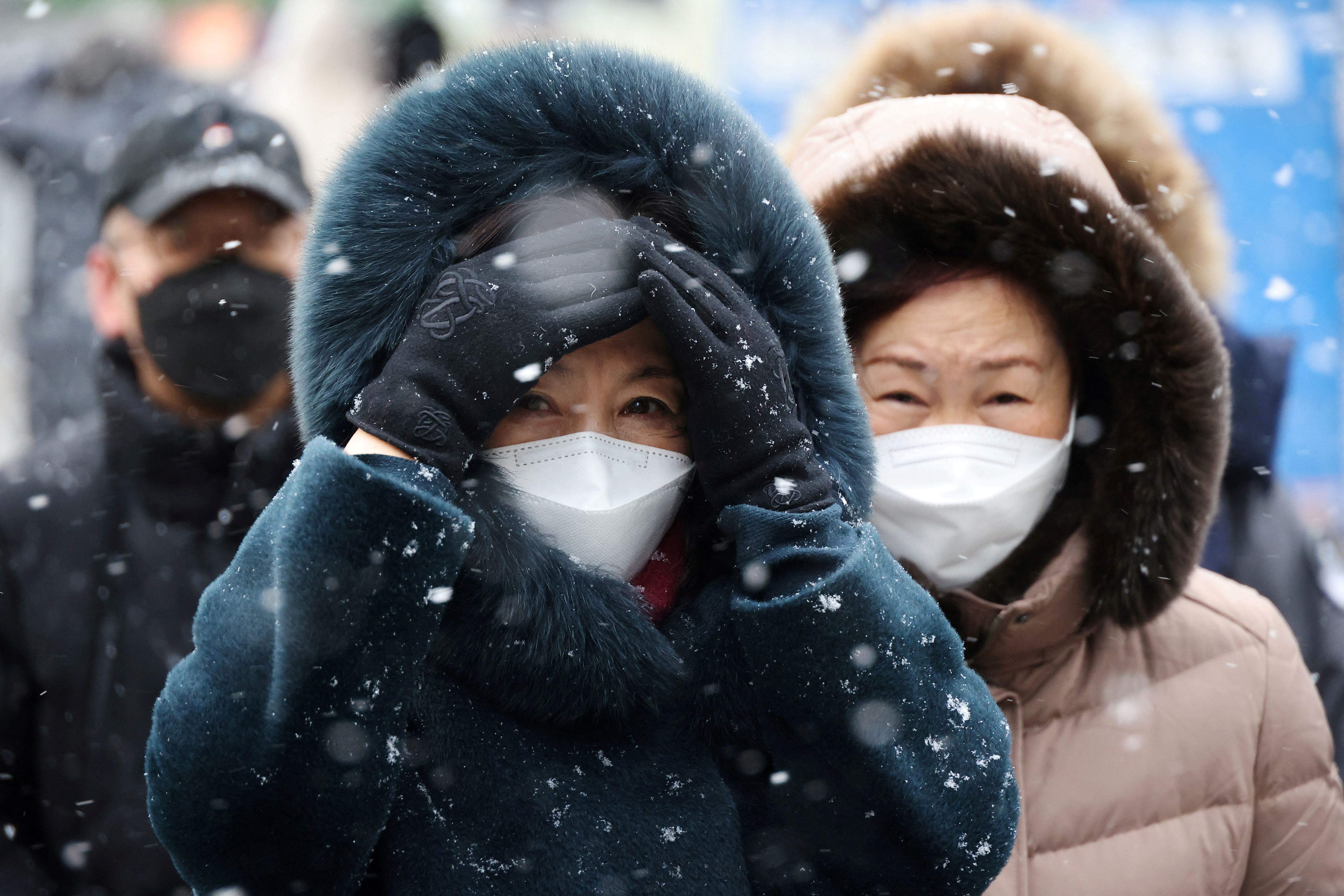 Commuters walk during snowfall, amid the coronavirus disease (COVID-19) pandemic, in central Seoul