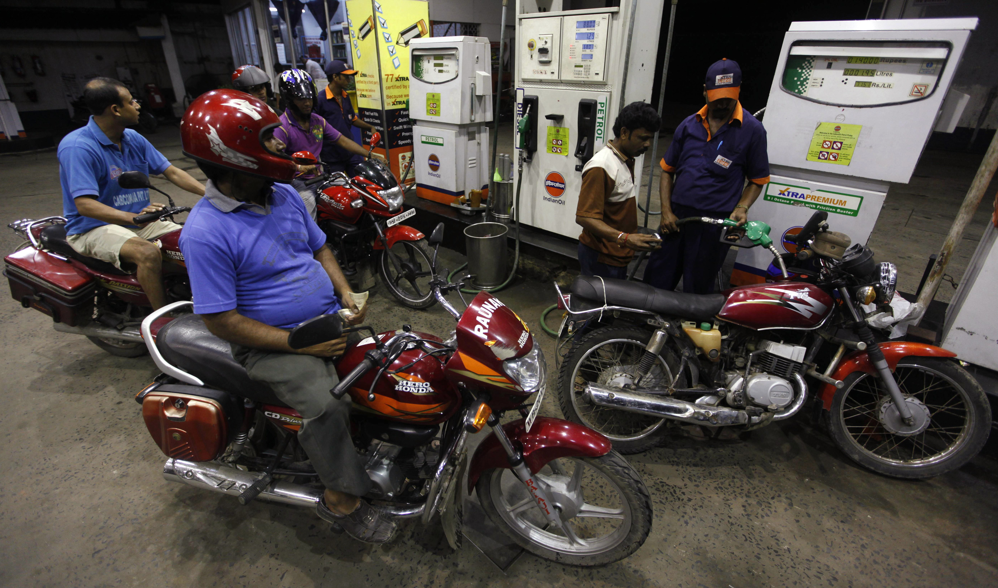 A worker fills a motorcycle with petrol at a fuel station in Kolkata