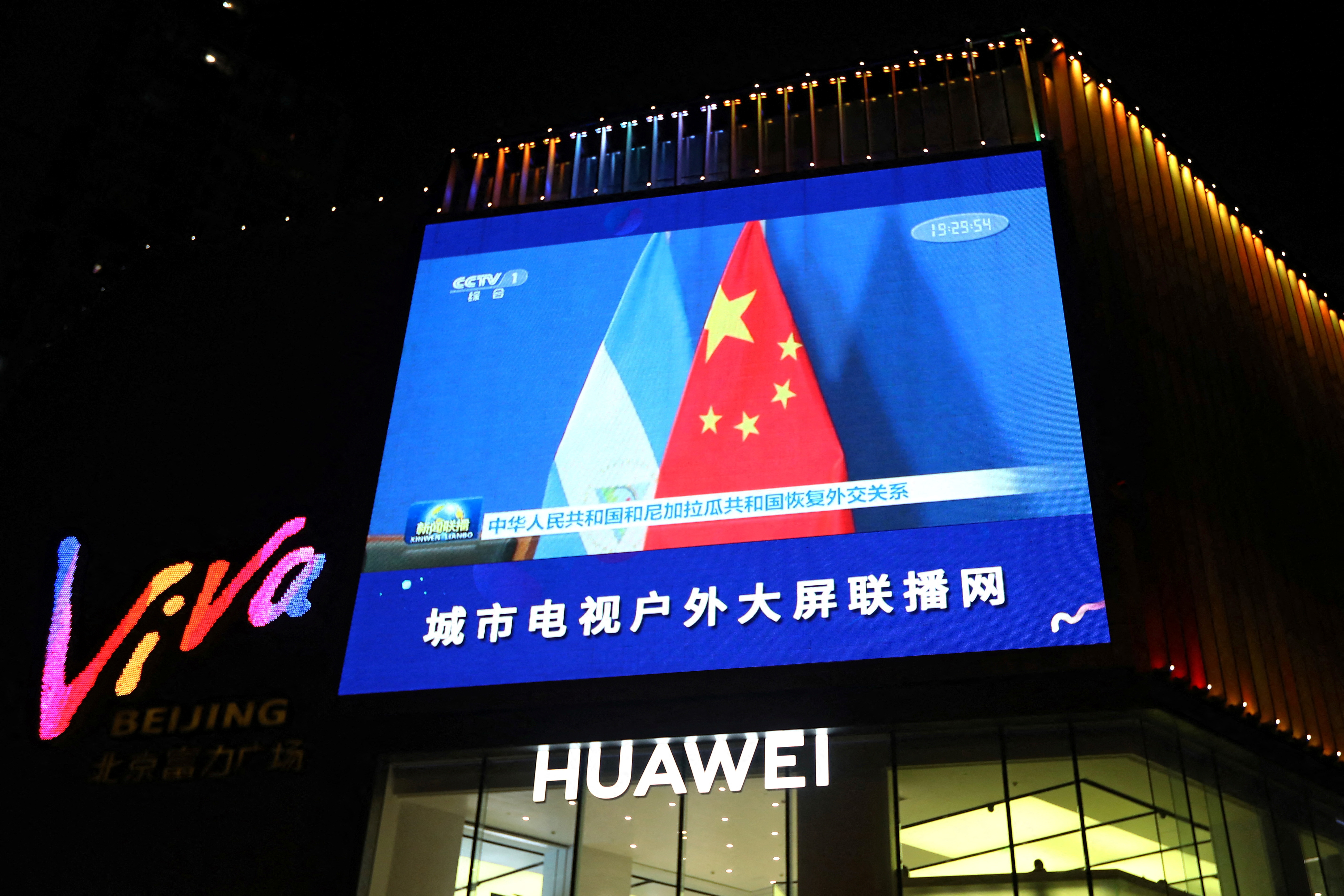 A screen shows news footage of flags of the People's Republic of China and the Republic of Nicaragua, in Beijing