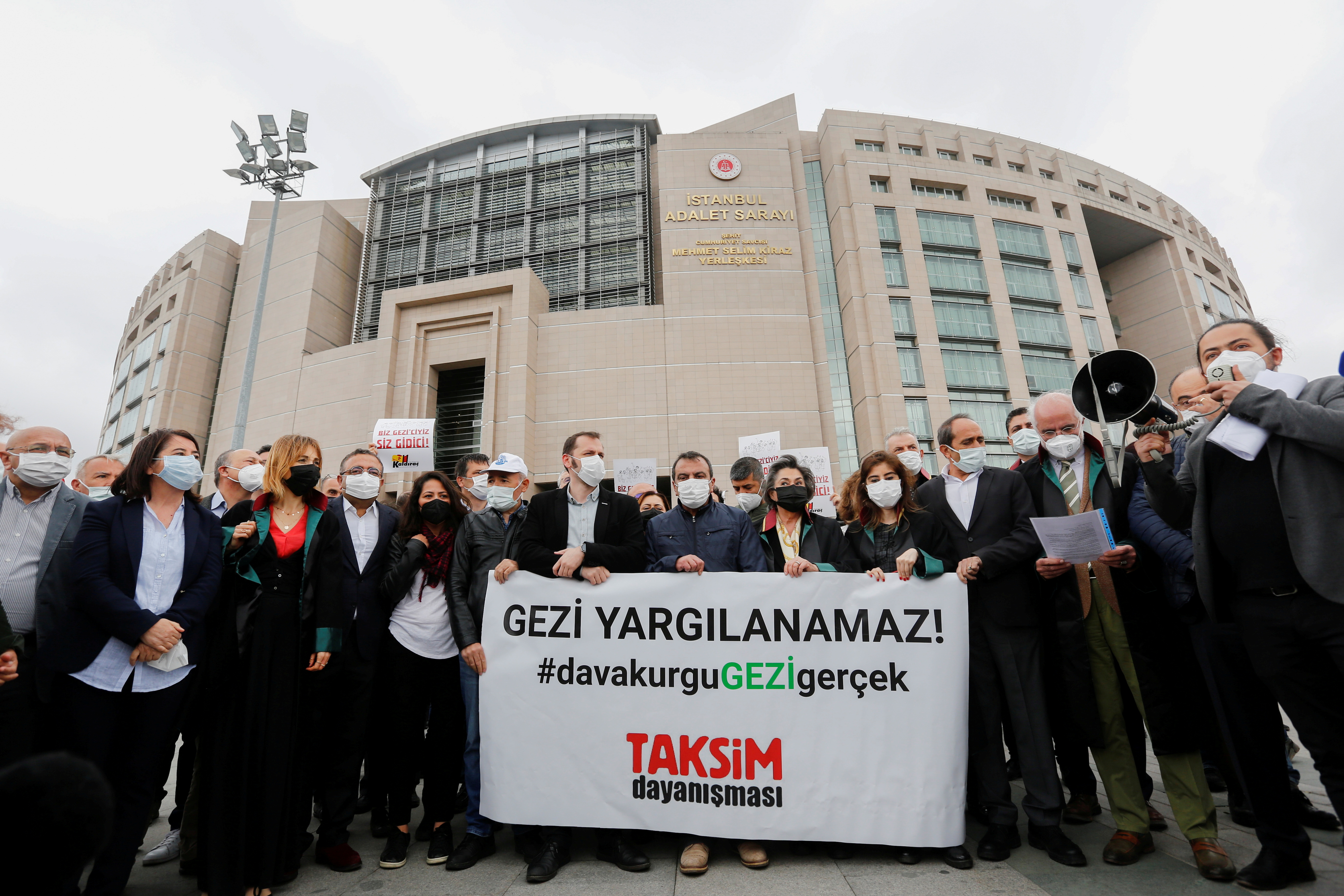 Lawyers and opposition lawmakers gather in front of the Justice Palace, the Caglayan Courthouse, as a Turkish court began the re-trial of philanthropist Osman Kavala and 15 others over their role in nationwide protests in 2013, in Istanbul, Turkey, May 21, 2021. The banner reads: 