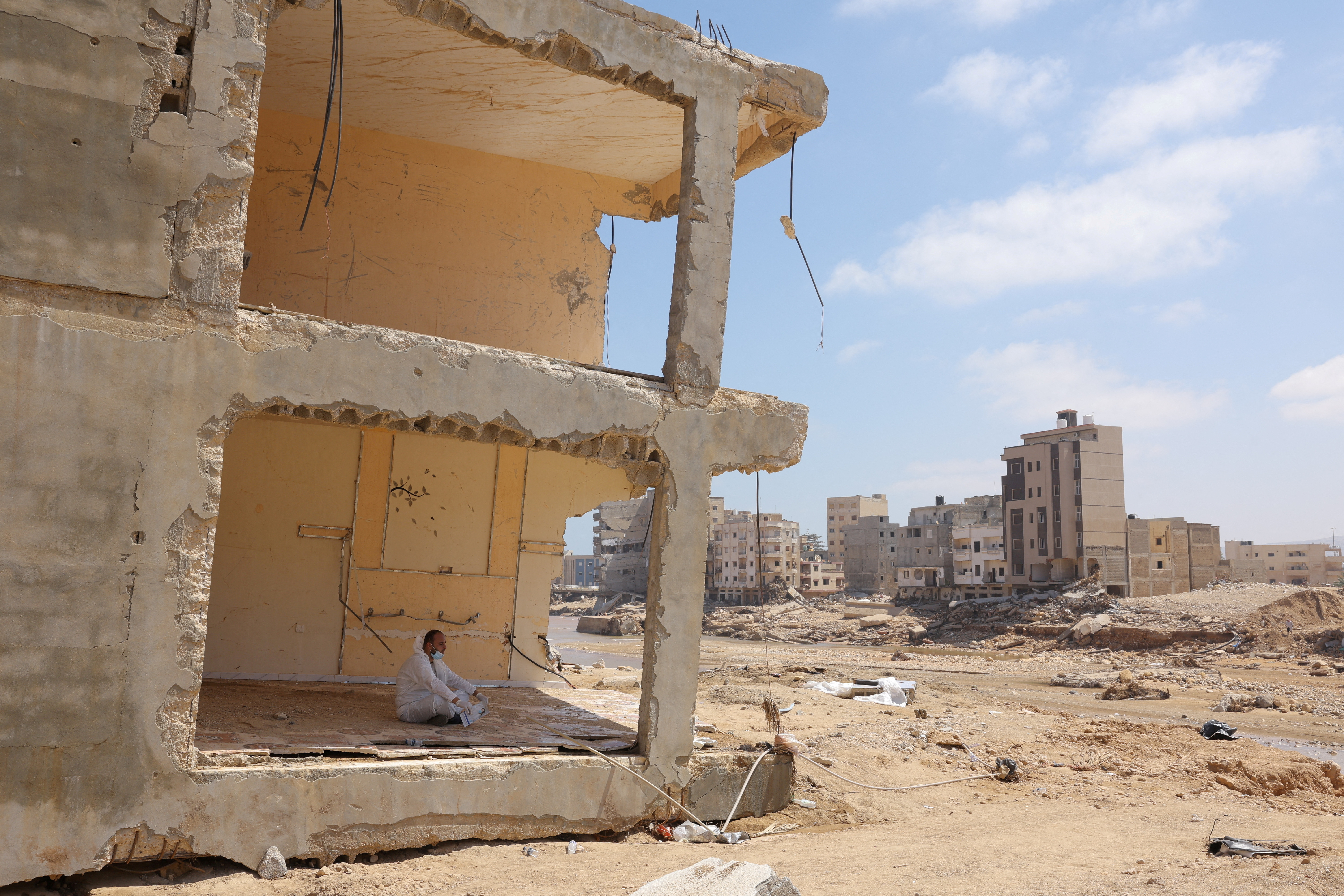 A volunteer rests inisde a destroyed home following fatal floods in Derna