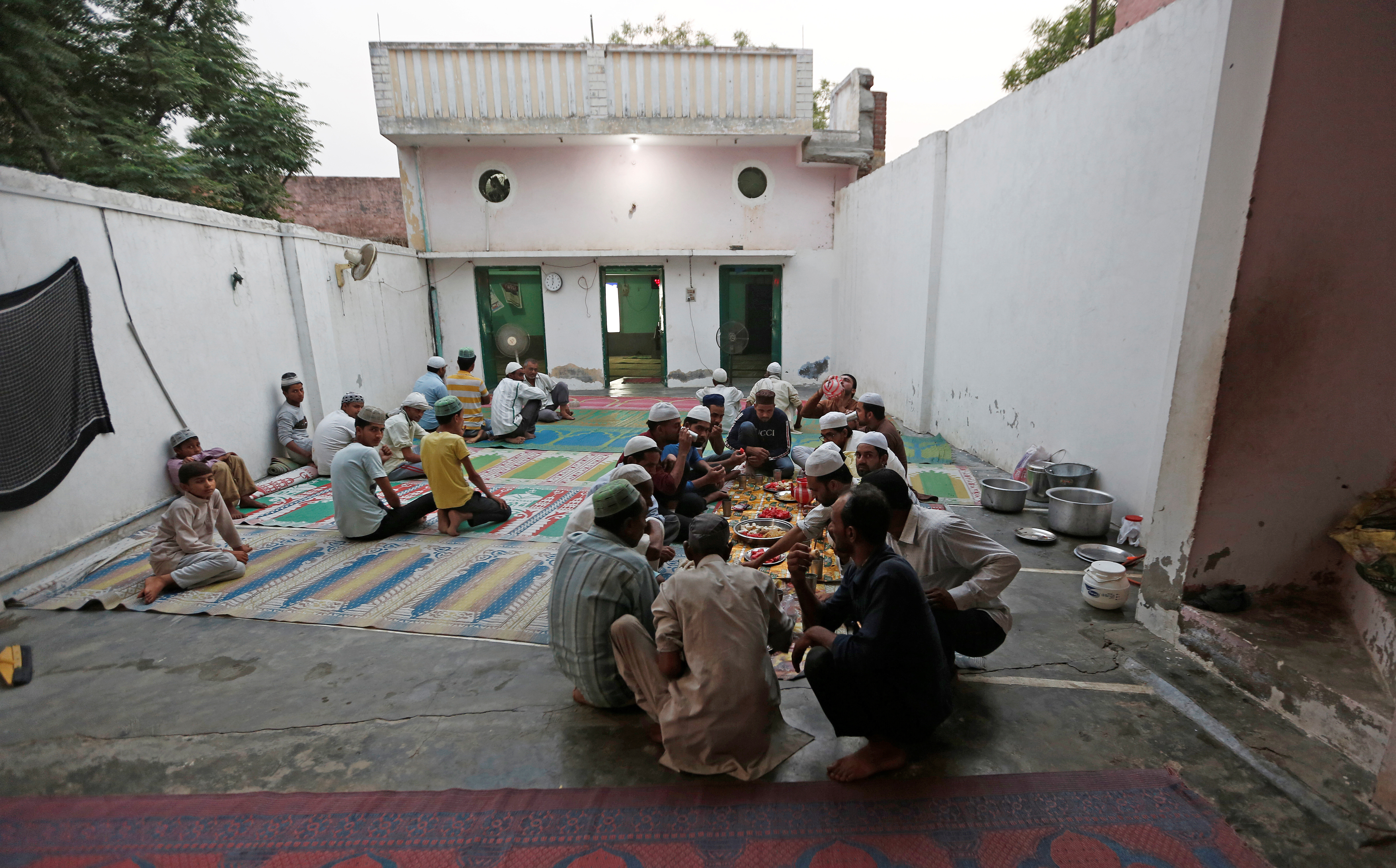 Muslims eat their Iftar (breaking of fast) meal during the holy month of Ramadan inside a madrasa that also acts as a mosque in village Nayabans