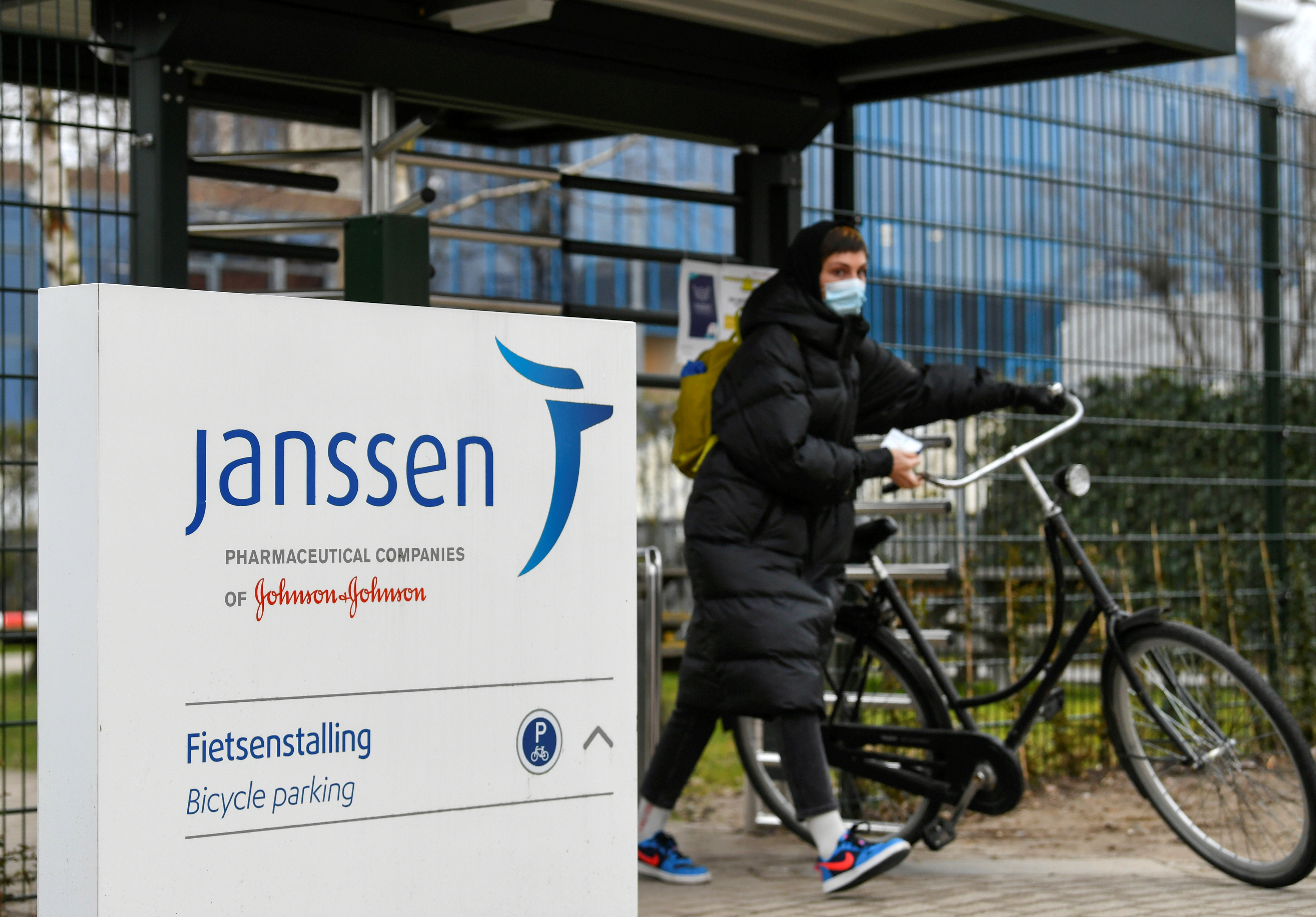 A woman leaves with her bike at Johnson and Johnson's subsidiary Janssen Vaccines in Leiden
