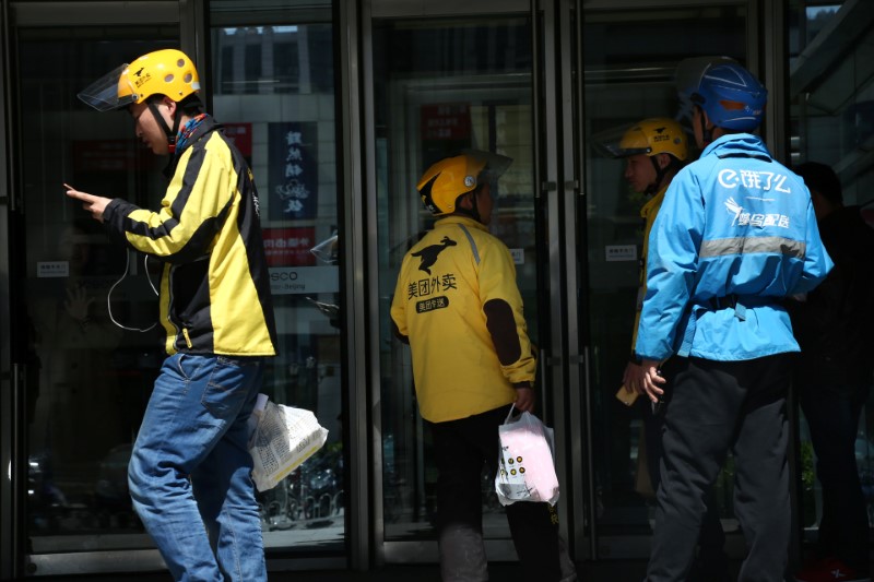 Drivers of food delivery service Ele.me (in blue) and Meituan (in yellow) are seen in Beijing