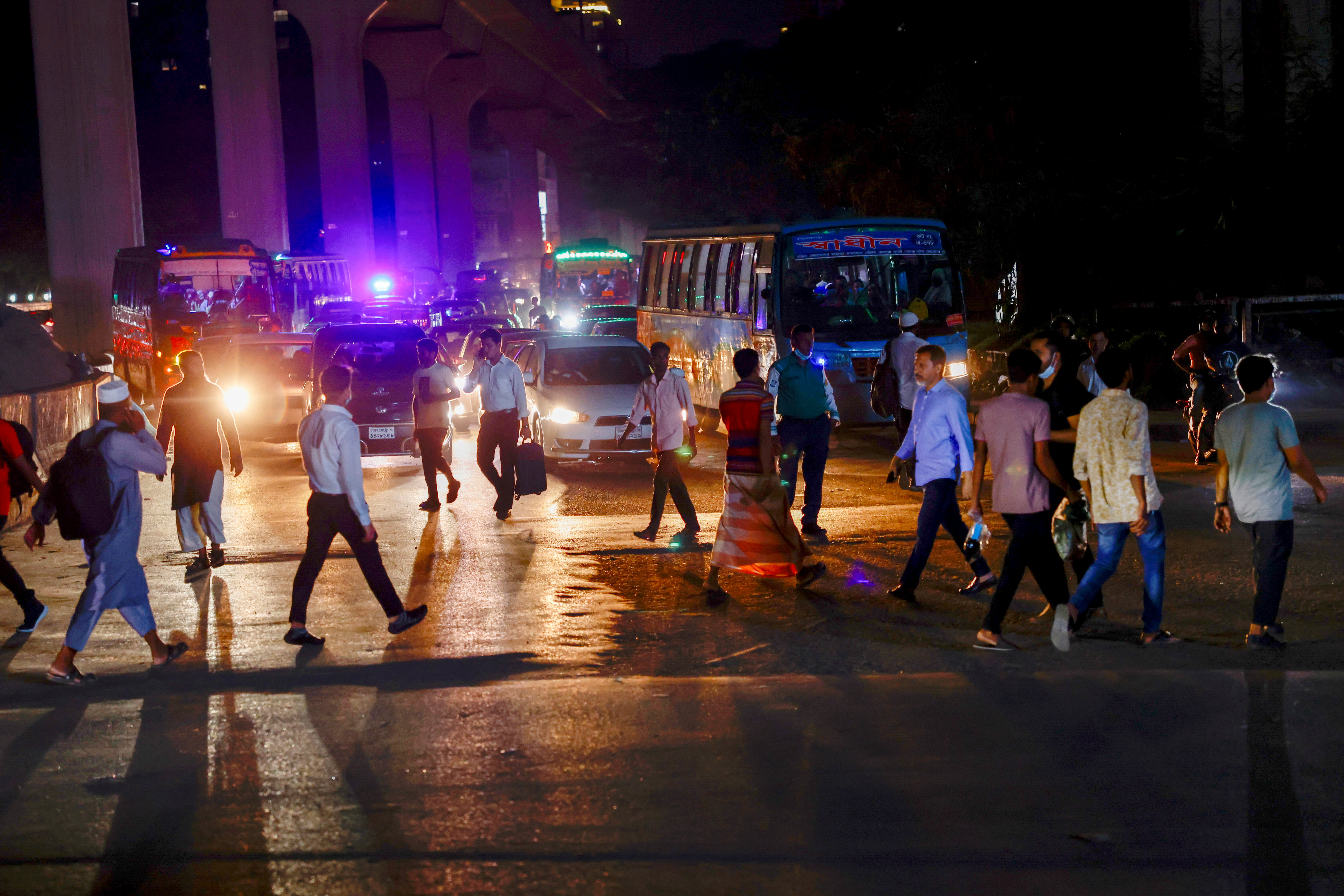 People cross a road at night in Dhaka