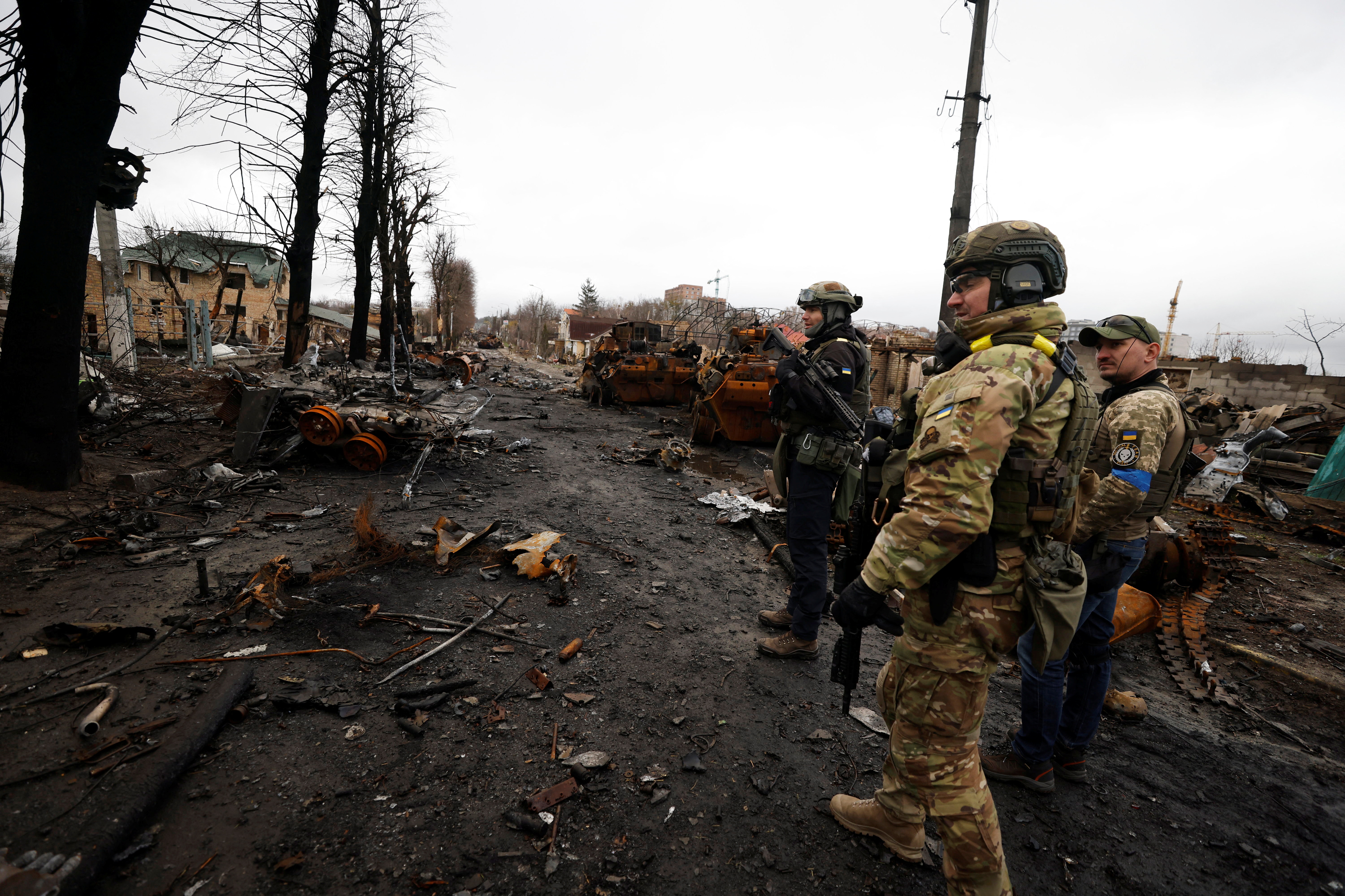 Soldiers walk to see destroyed Russian military vehicles, amid Russia's invasion on Ukraine in Bucha, in Kyiv region