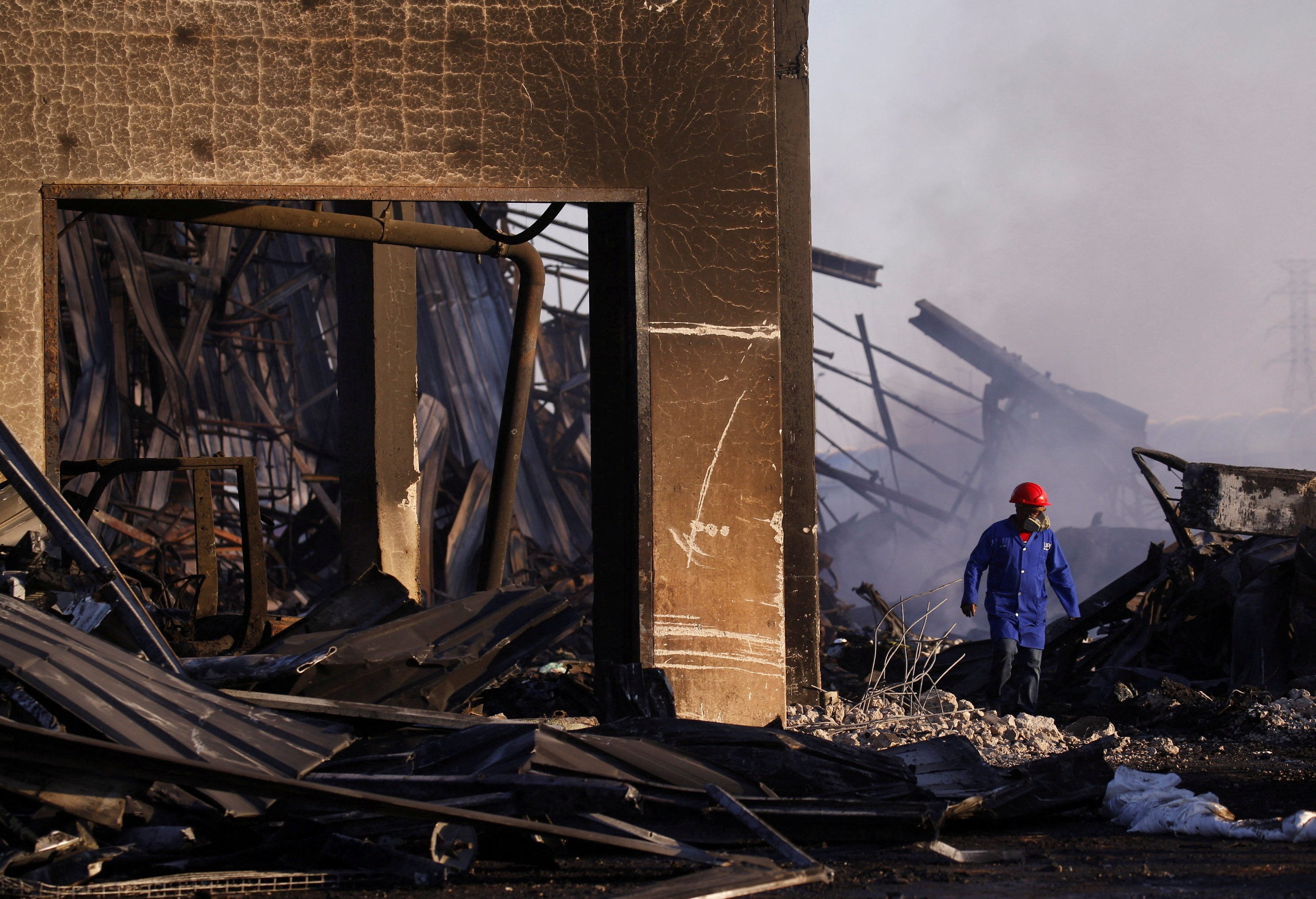 A man walks through the remnants of a warehouse which was burned during days of looting, in Durban