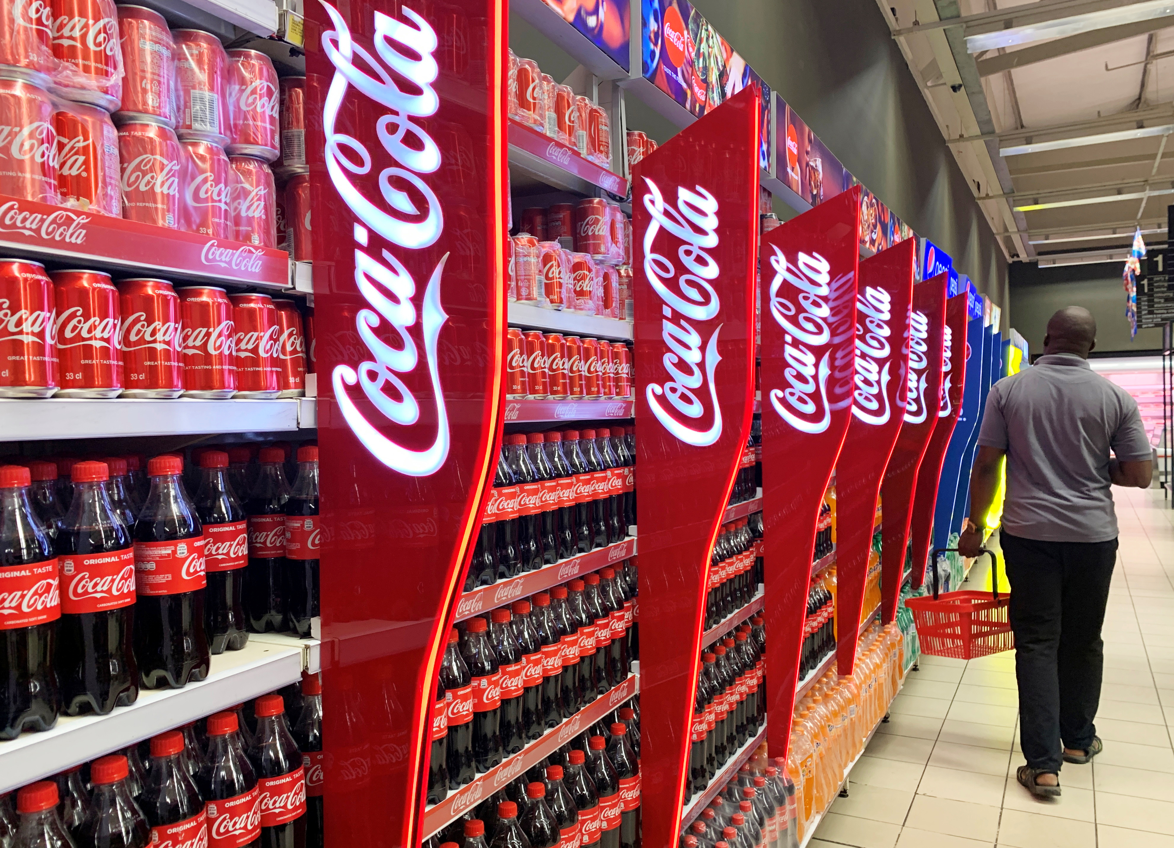 A man walks past shelves of Coca-Cola bottles and cans at a Shoprite store inside Palms shopping mall in Lagos