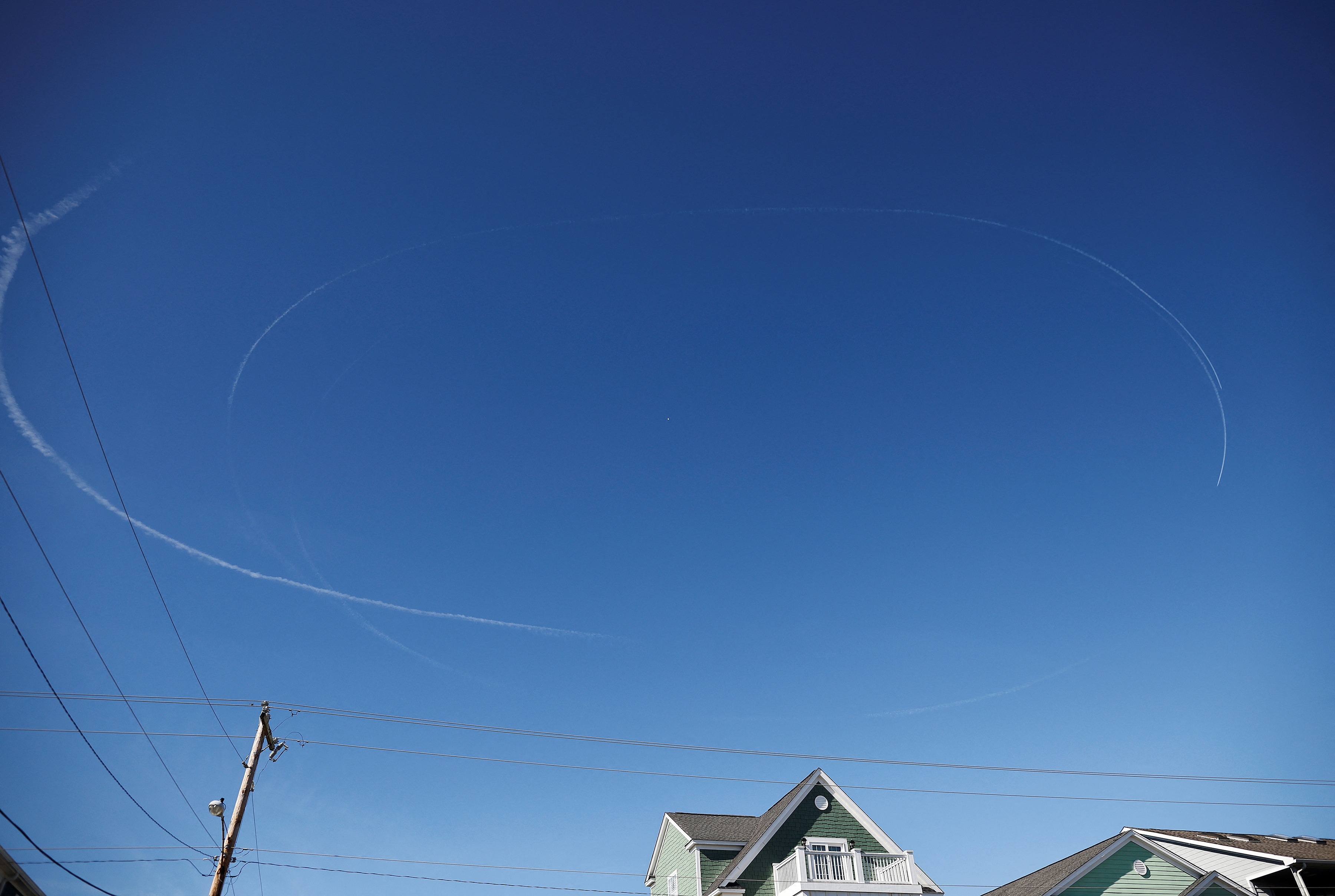 Contrails from jets circle a suspected Chinese spy balloon as it floats off the coast in Surfside Beach