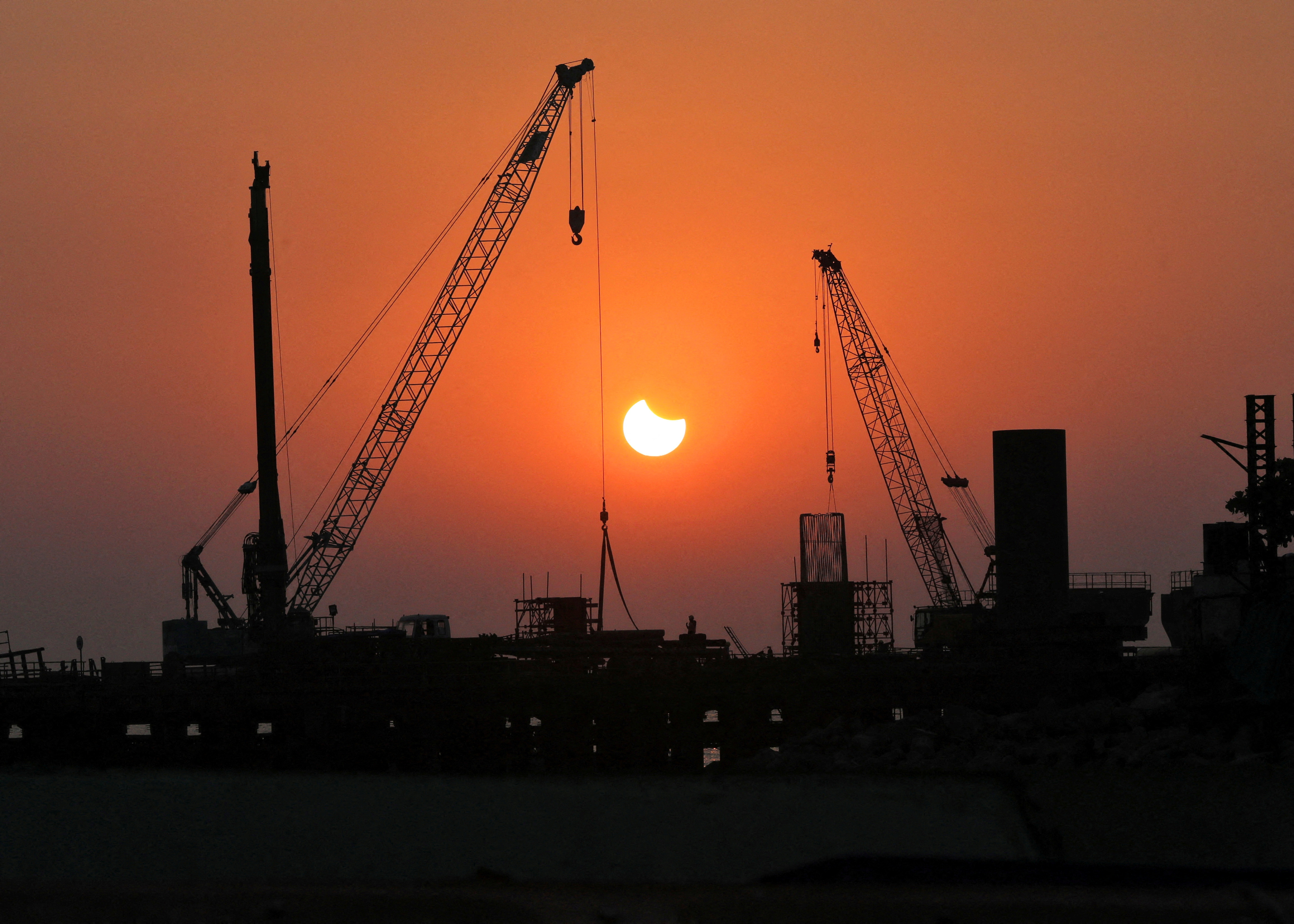 A partial solar eclipse is seen at a construction site in Mumbai