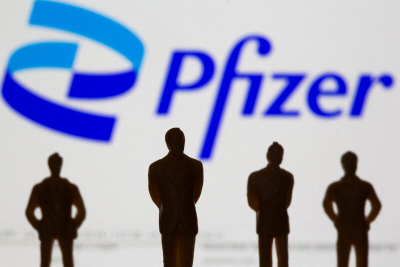 FILE PHOTO: Small toy figures are seen in front of displayed Pfizer logo in this illustration taken, June 24, 2021. REUTERS/Dado Ruvic/Illustration