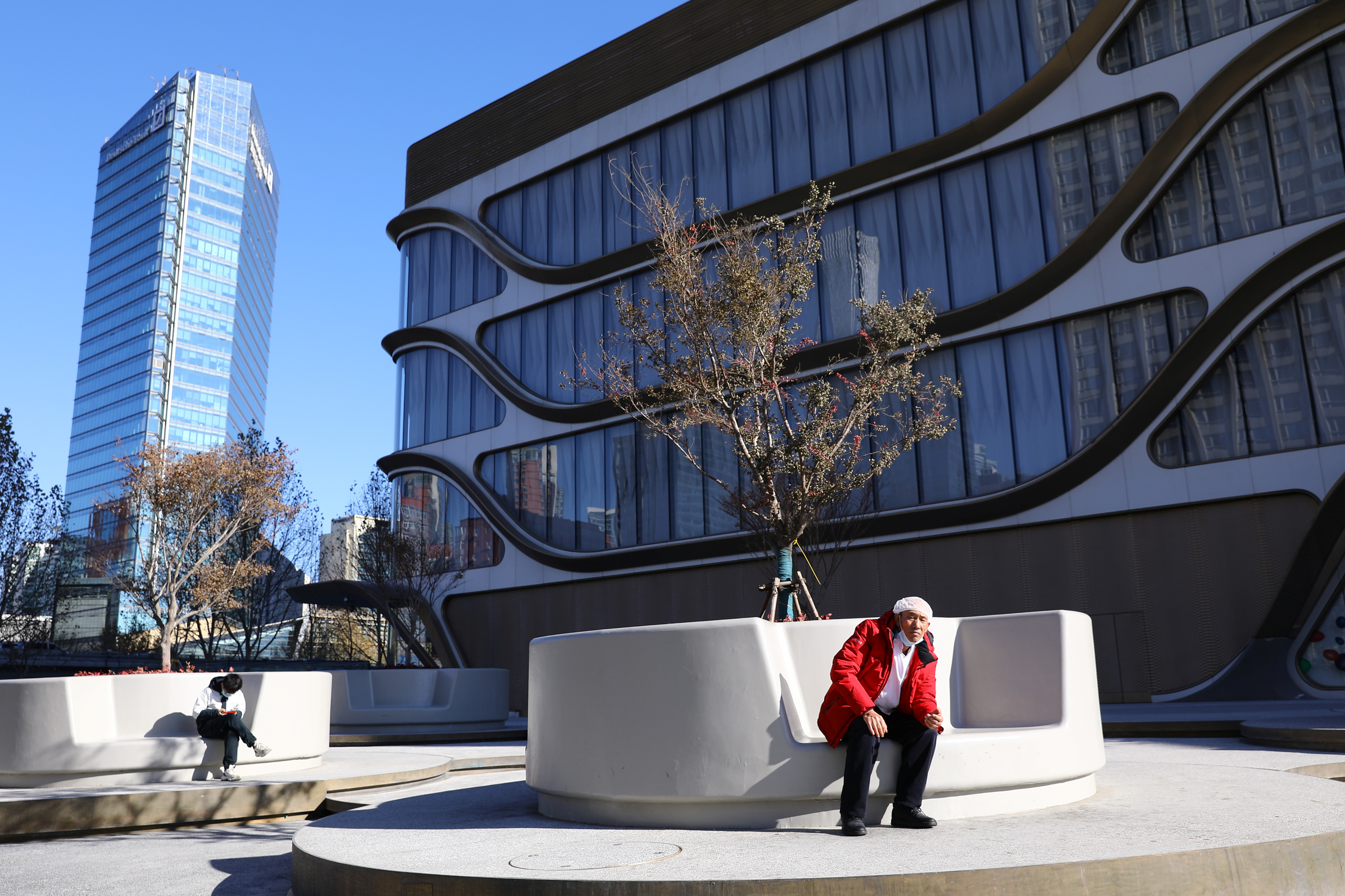 A man rests in front of a shopping mall at the Kaisa Plaza, a real estate property developed by Kaisa Group Holdings, in Beijing, China December 1, 2021. REUTERS/Tingshu Wang