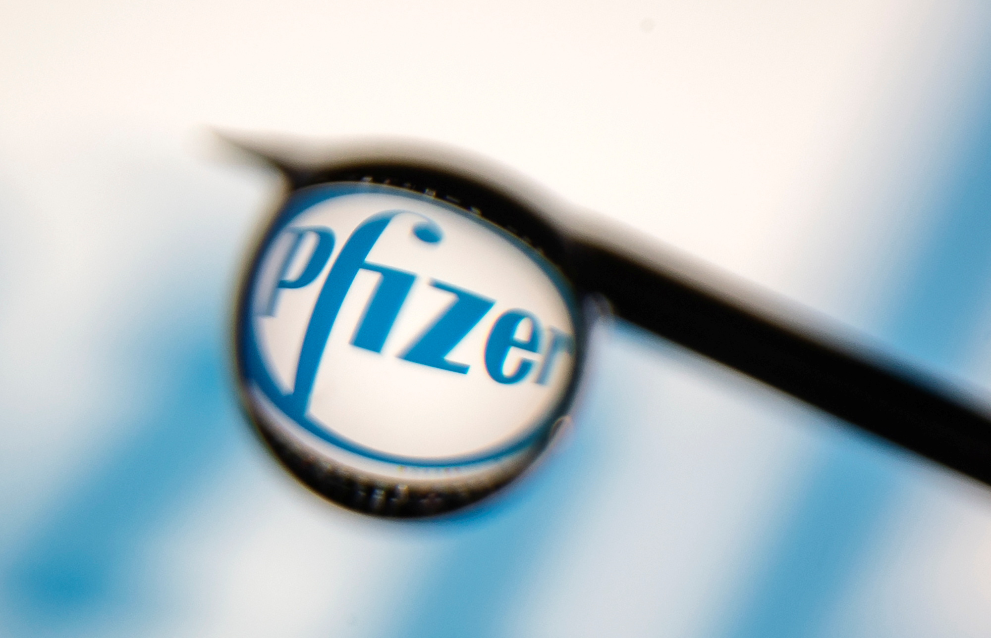 Pfizer logo is reflected in a drop on a syringe needle in this illustration photo