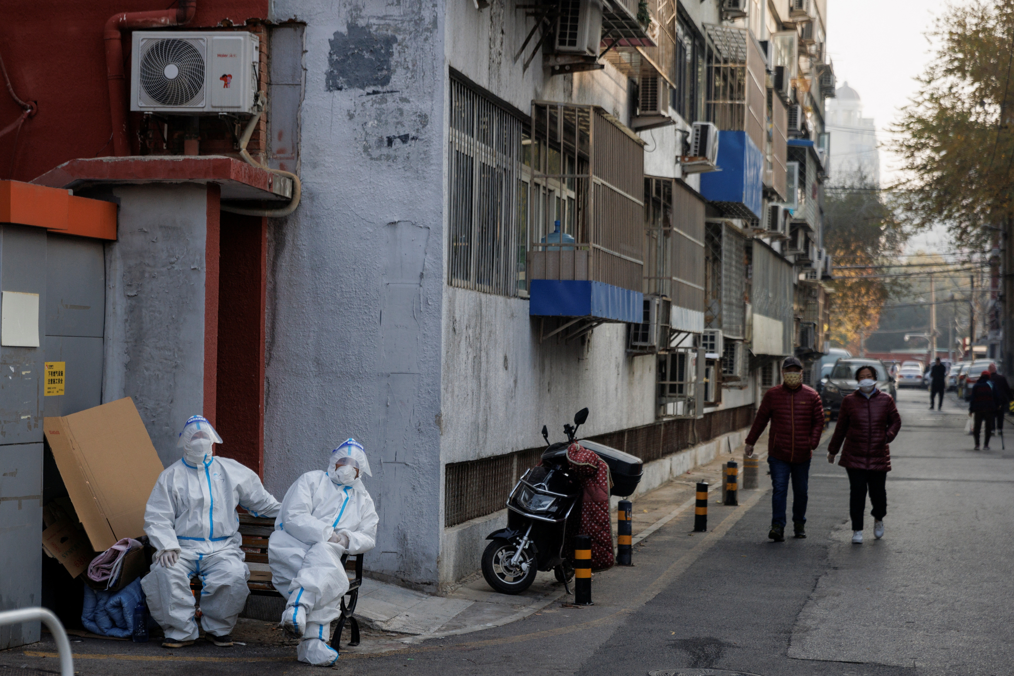 Epidemic preven   tion workers in protective suits sit in a locked-down residential compound as outbreaks of the coronavirus disease (COVID-19) continue in Beijing